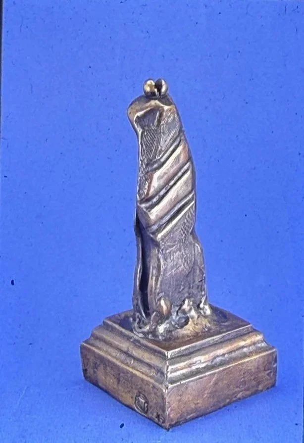 Tall bronze sculpture featuring a slender standing figure integrated into a twisting vertical form mounted on a square base.