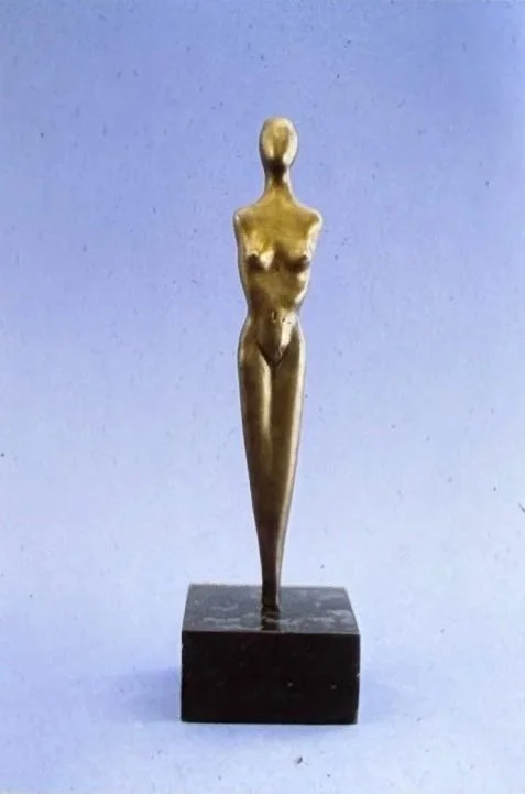 Extremely elongated bronze figure standing erect on a square plinth, the body tapering into a sleek, almost needle-like silhouette.