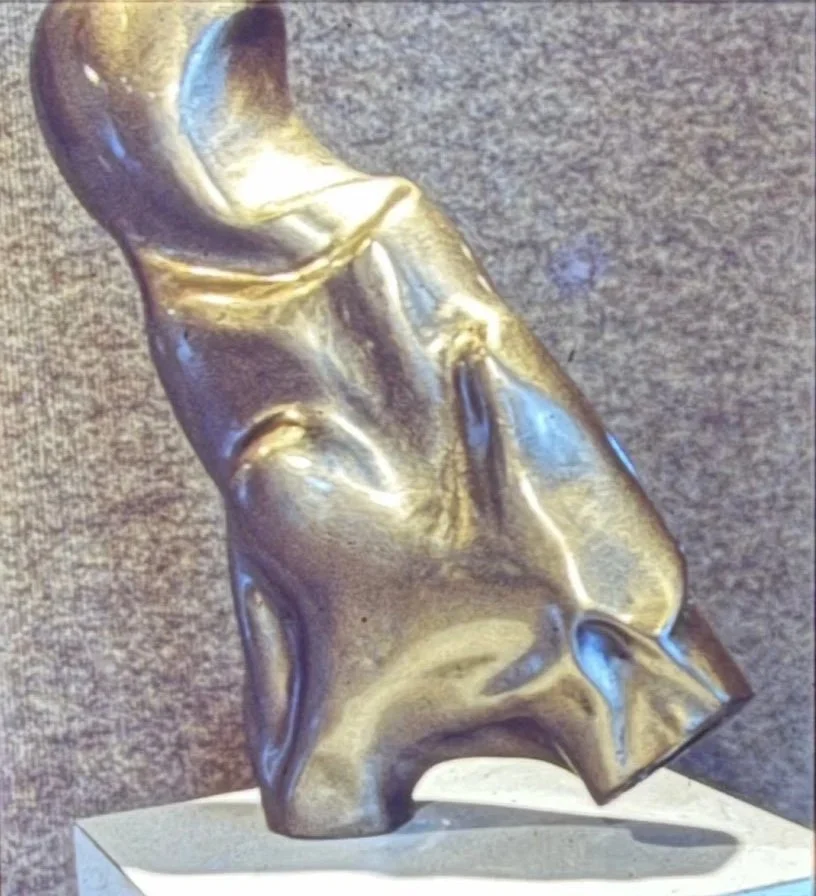 Highly abstract bronze form balancing horizontally from a small pedestal, resembling a diver suspended in midair.