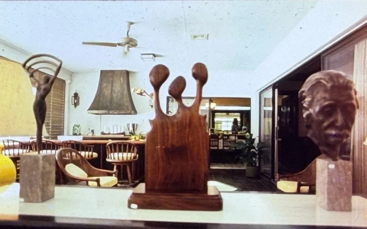 Interior room displaying multiple sculptures, including abstract wood carvings and portrait busts.