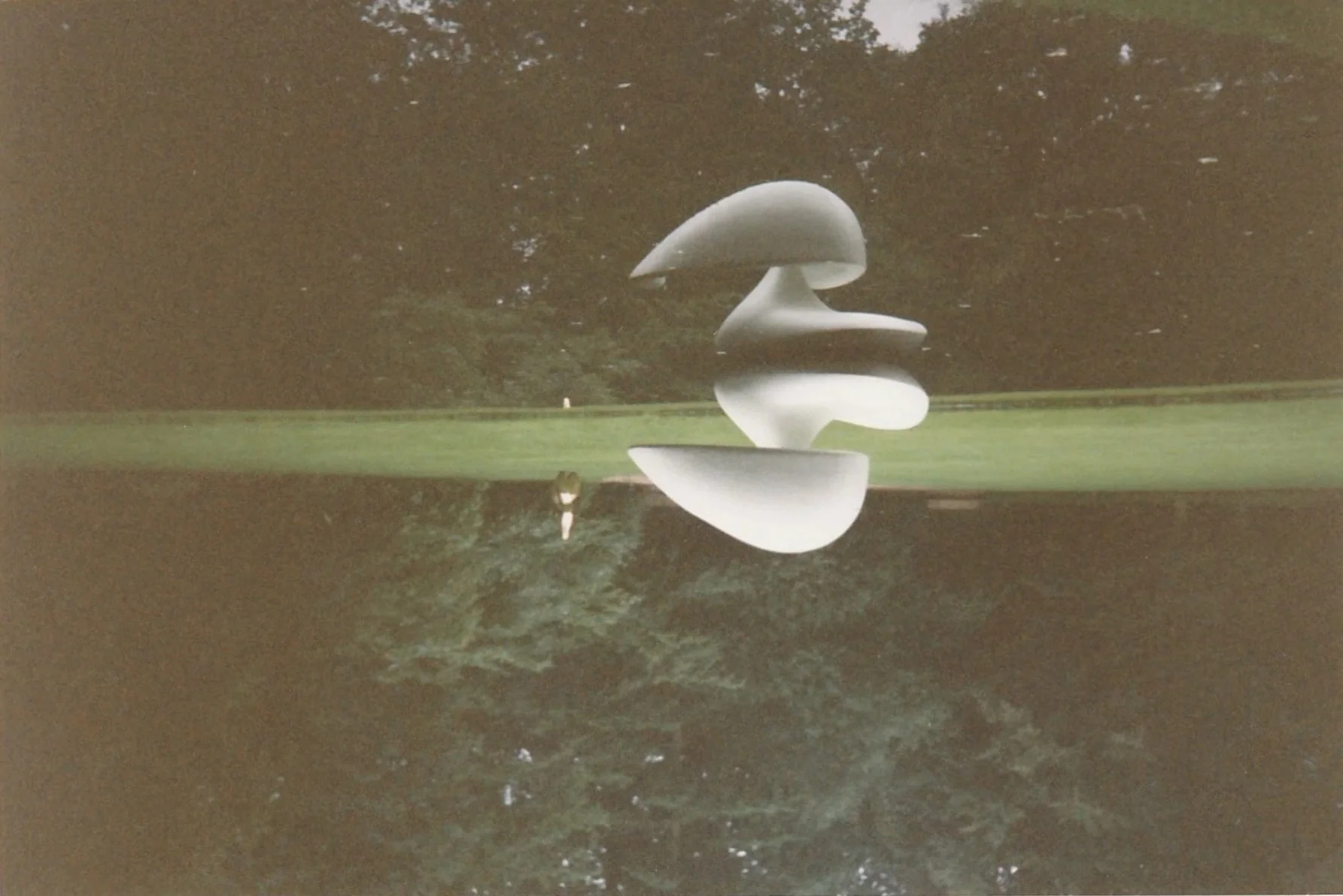 Abstract white sculpture composed of stacked curved forms reflected across a calm body of water.
