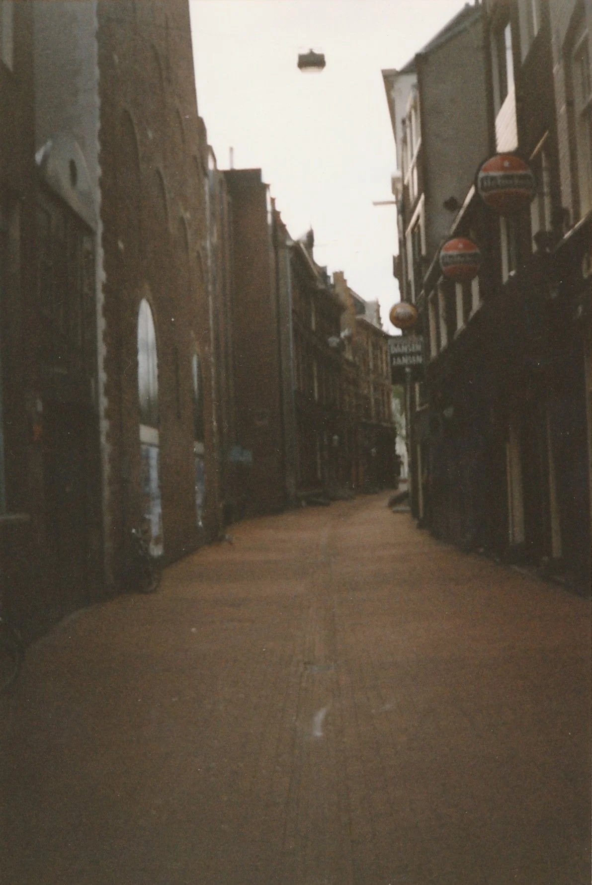 Narrow city alley lined with brick buildings, illuminated by soft afternoon light.
