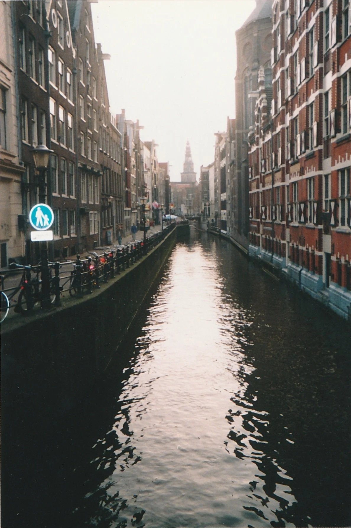 Narrow canal bordered by tall historic buildings reflected in still water.
