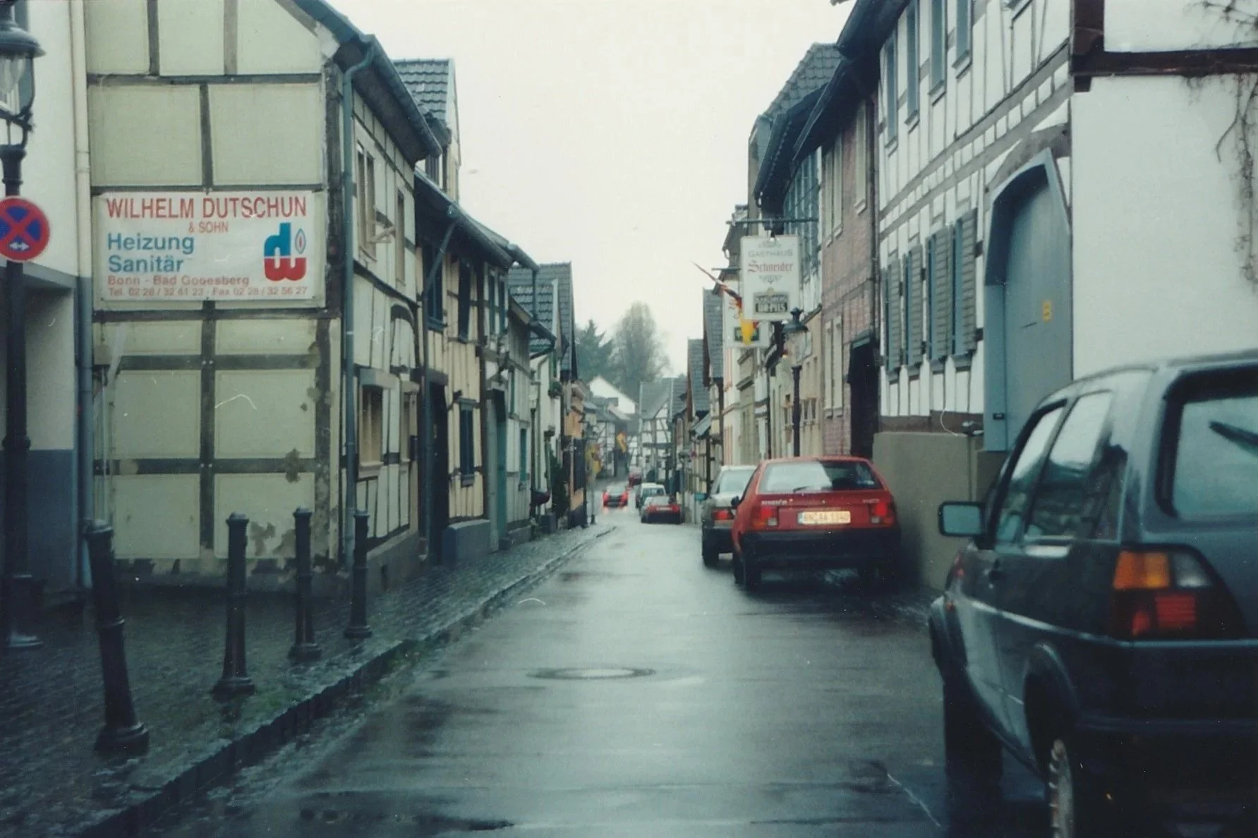 Narrow European street lined with half-timbered buildings glistening after rain.