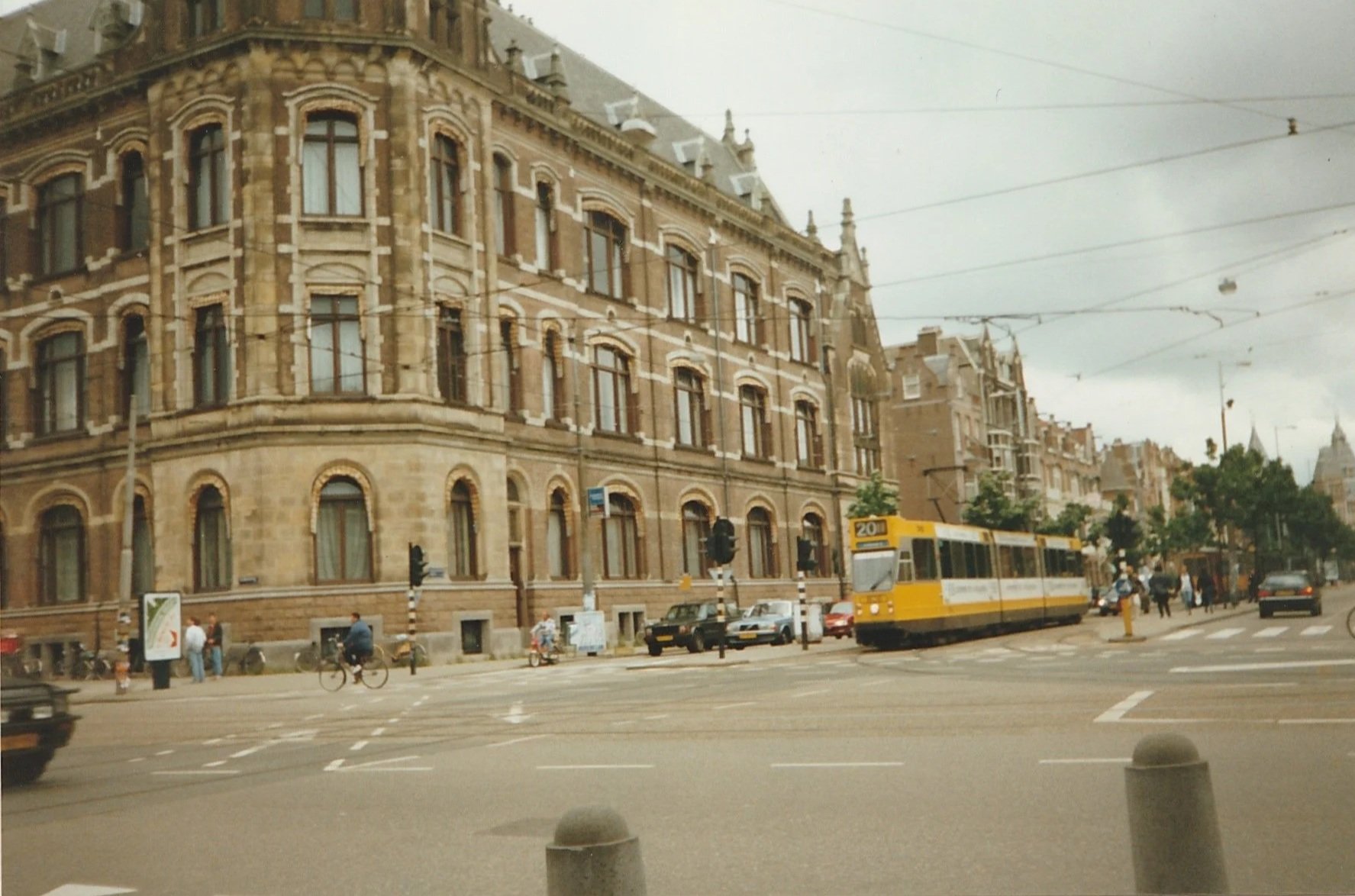 Ornate stone building at a busy city intersection with trams and passing traffic.