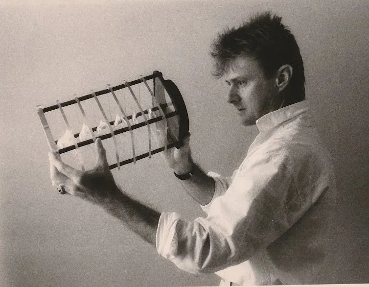 Whitney Wolf II featured in a black-and-white photo where he is looking into one of his scientific art works, side profile. Circa 1980s