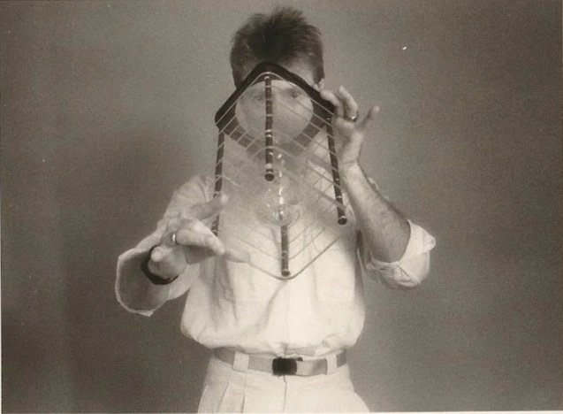 Whitney Wolf II featured in a black-and-white photo where he is looking into one of his scientific art works, straight ahead. Circa 1980s