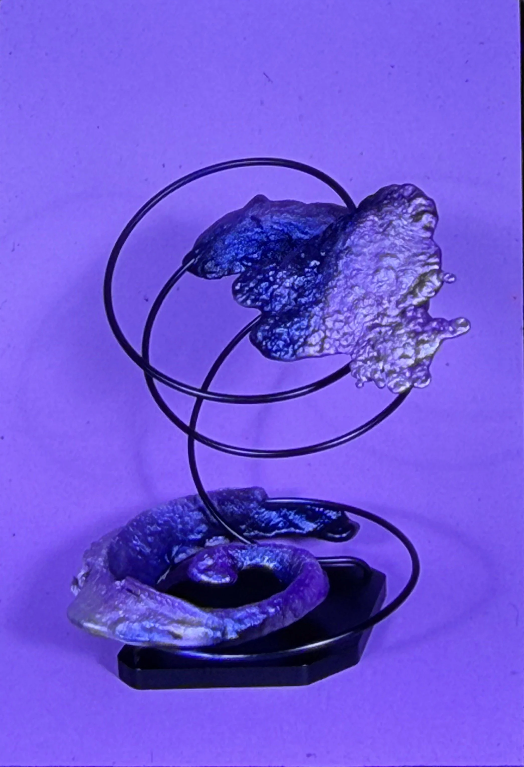 Abstract tabletop sculpture combining circular metal rings with textured organic elements.