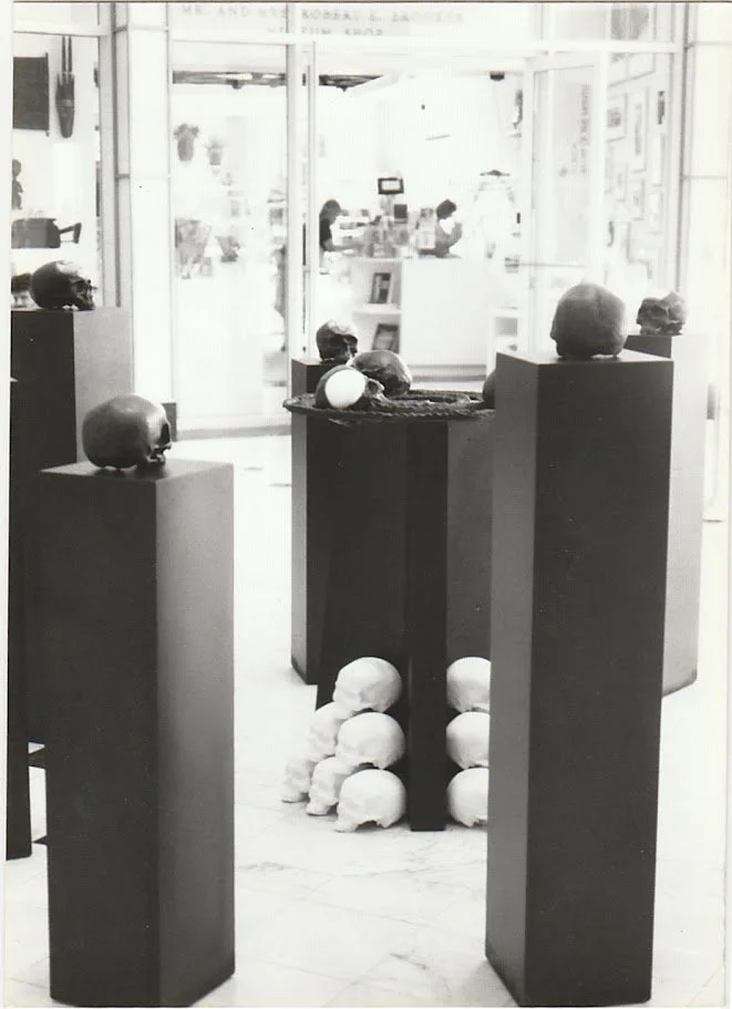 A grouping of skulls rests at the base of a central pedestal, while additional skull forms are displayed above and around the installation.