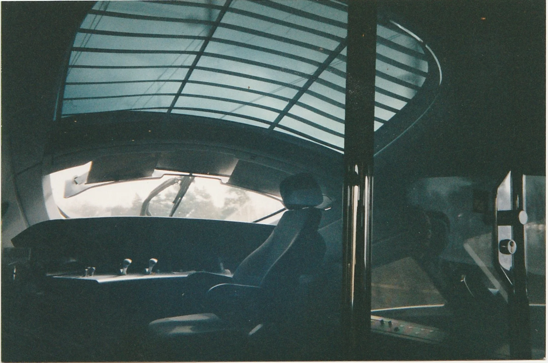 Futuristic glass-roofed interior viewed from inside a modern vehicle or observation space.