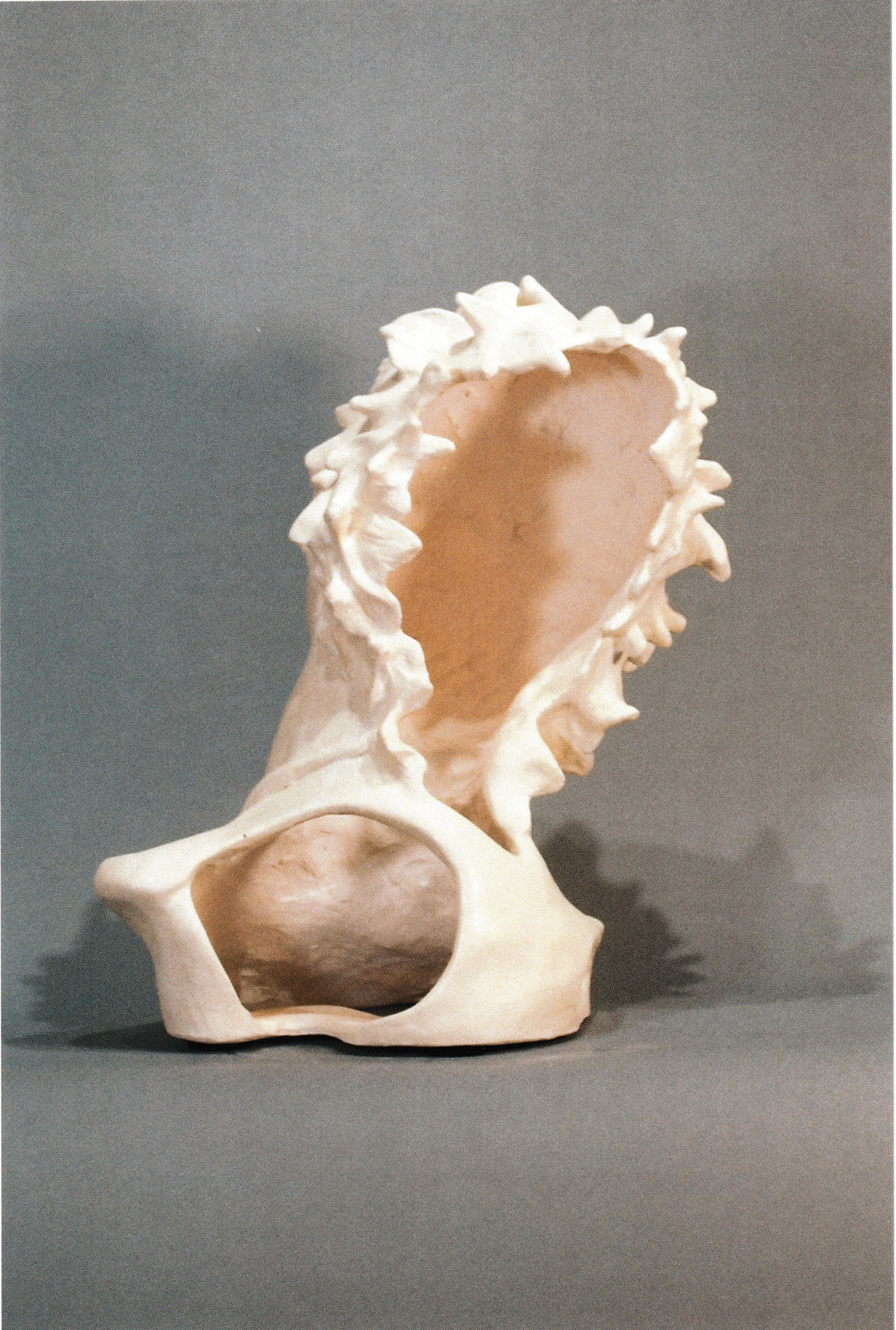Back Side View of the Stylized life-mask-derived ceramic portrait framed by jagged petal-like forms radiating outward. The back has a hollow and large open cavity.