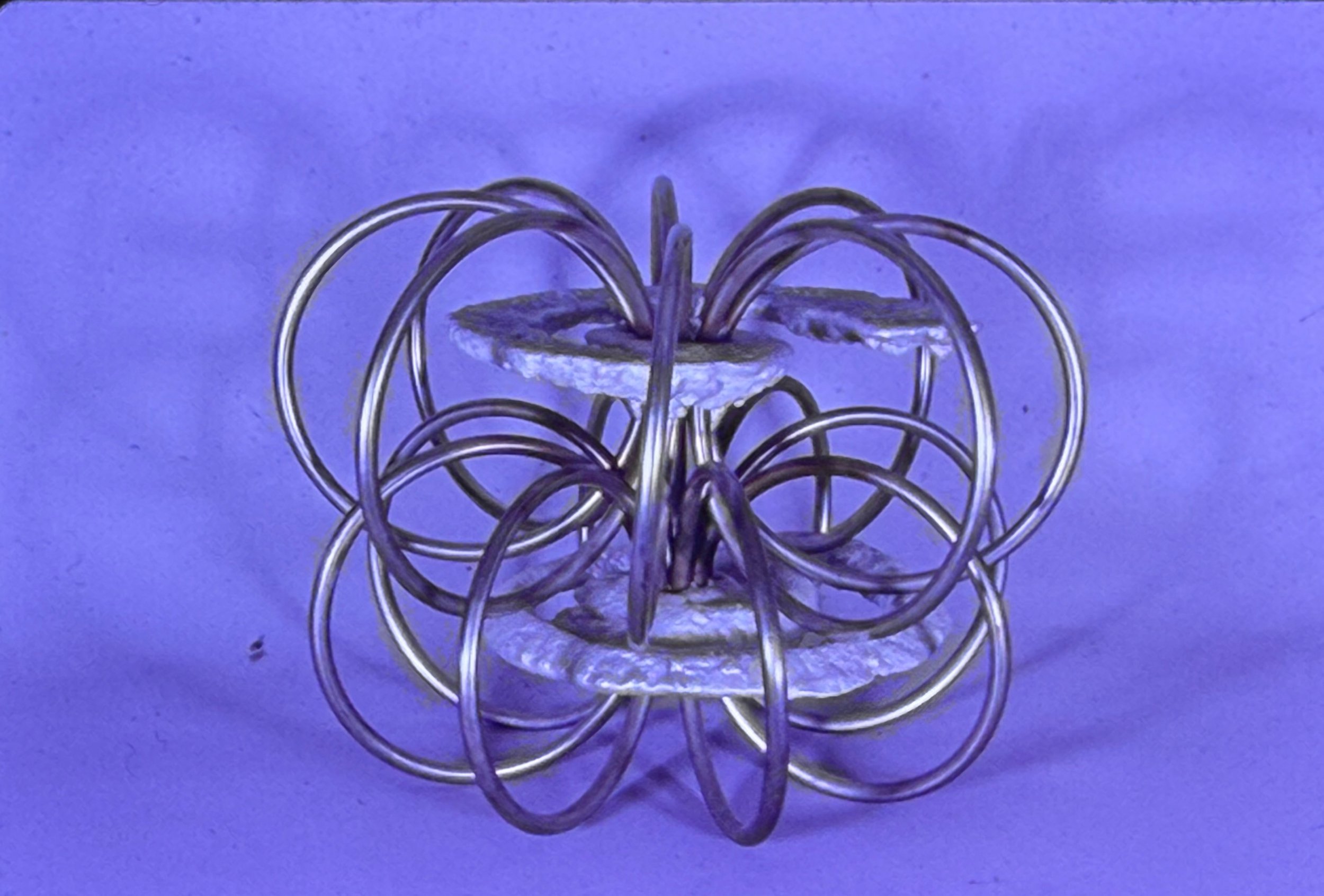 Metal sculpture composed of interlocking circular rings surrounding a central textured form.