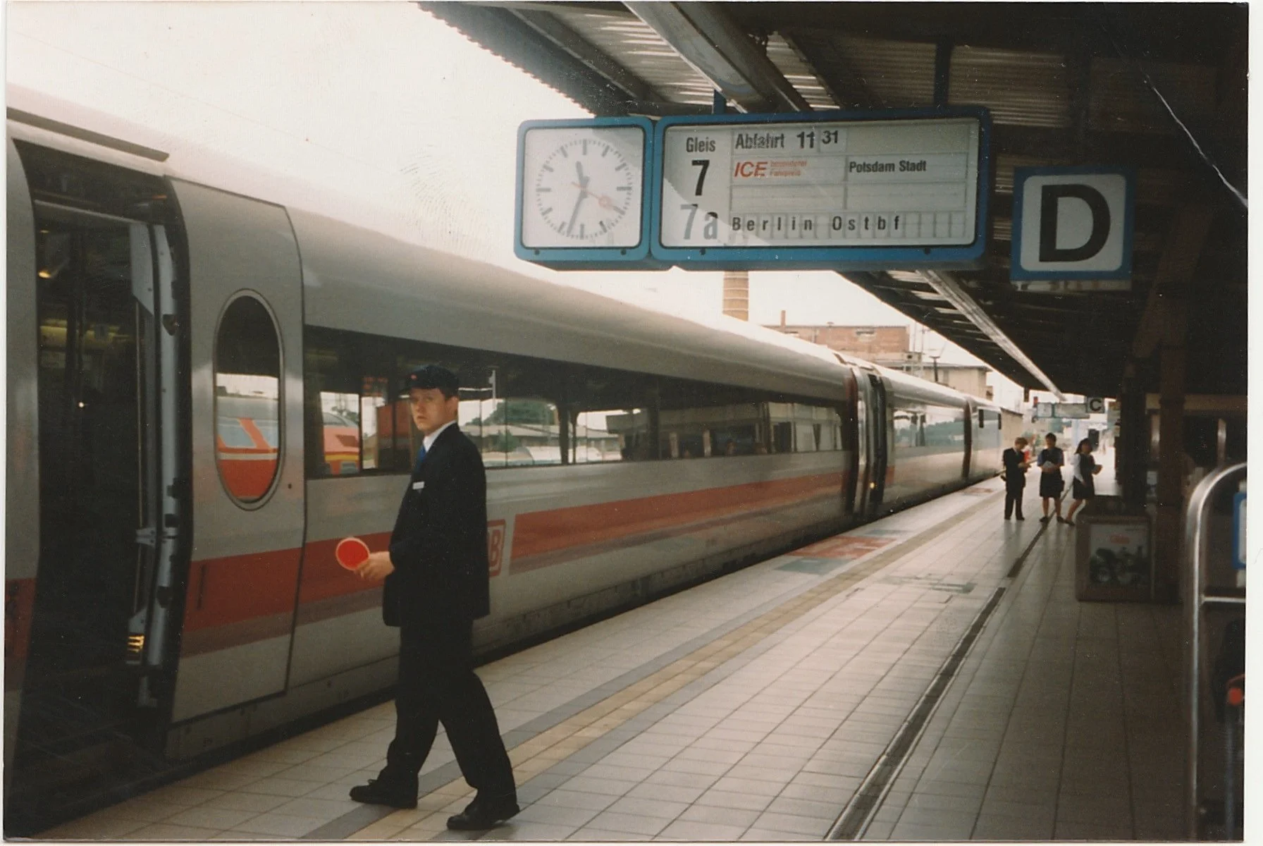 High-speed train waiting at a station platform as passengers walk nearby.
