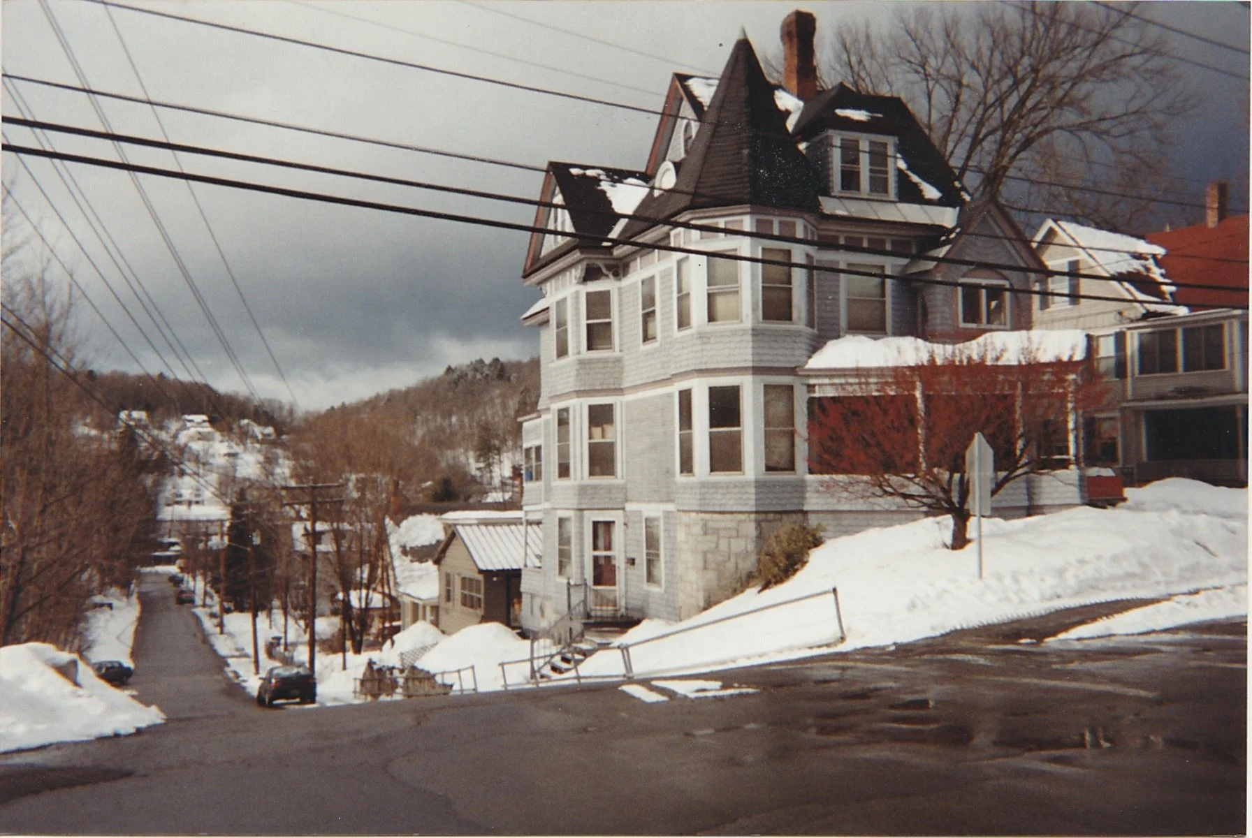 Large Victorian-style house overlooking snow-covered streets and hills.