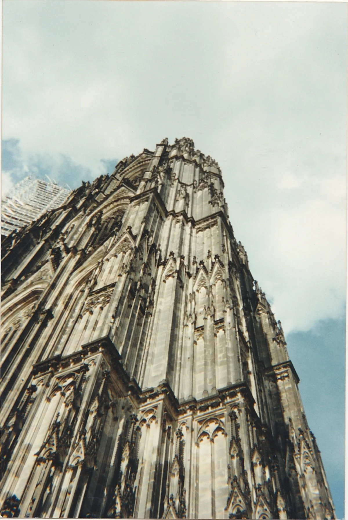 Dramatic upward view of a cathedral tower against a cloudy sky.