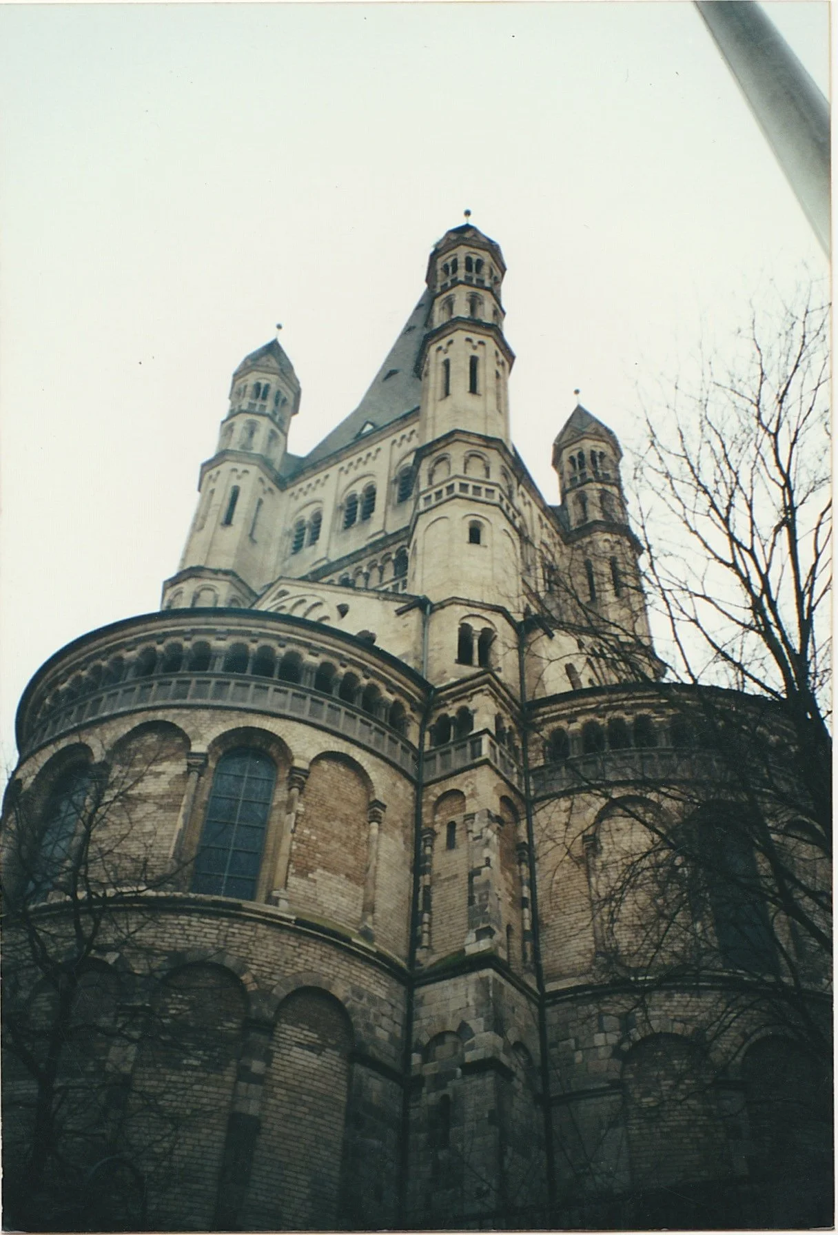 Romanesque church with rounded towers and weathered stone walls viewed from below.