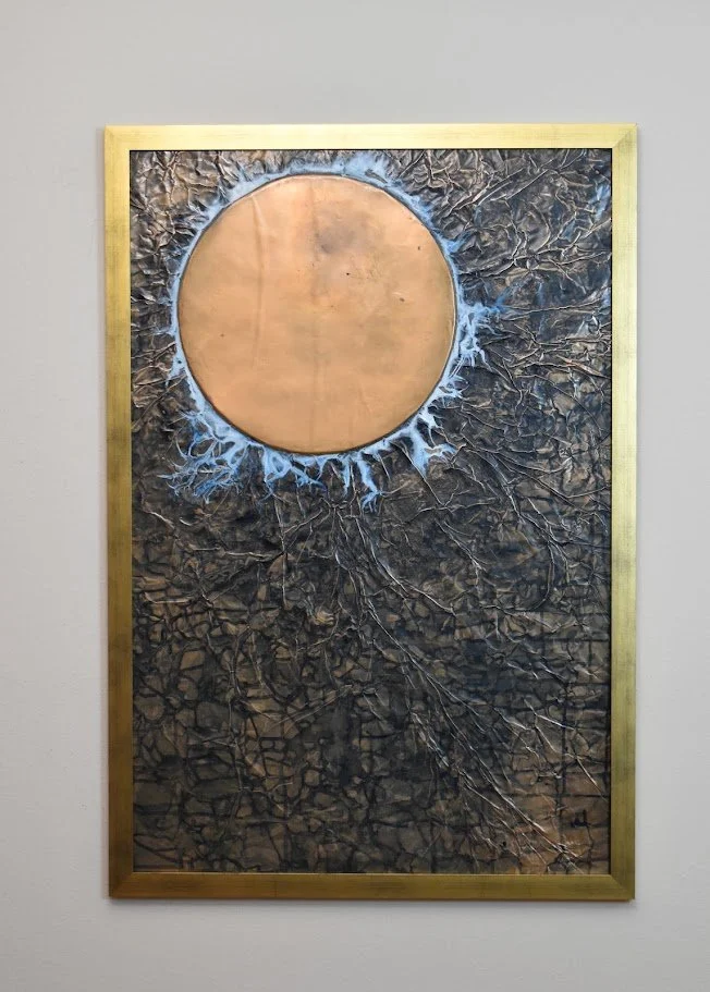 A copper orb glows against a dark, fractured field. Displayed framed on a white wall.
