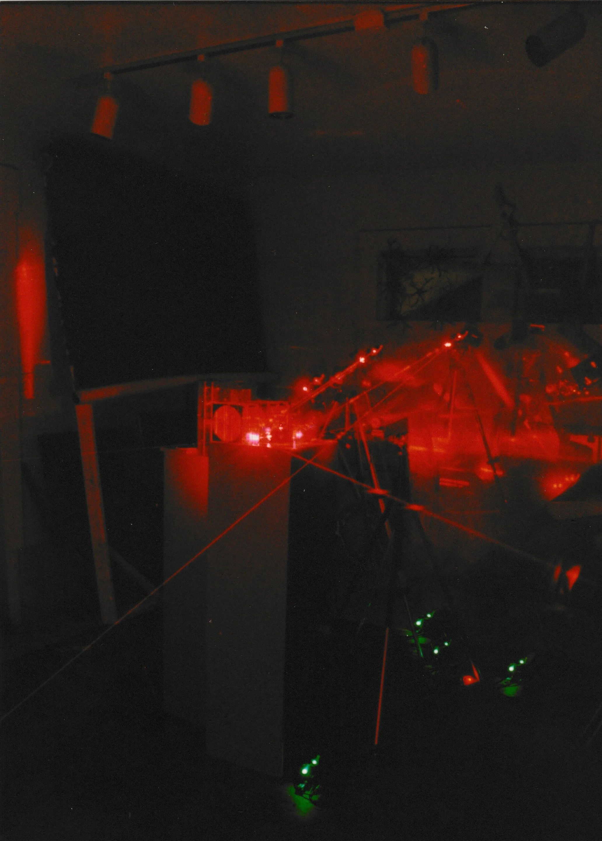 Bright red laser beams converge around a central sculptural form, creating energetic patterns of light throughout the gallery.