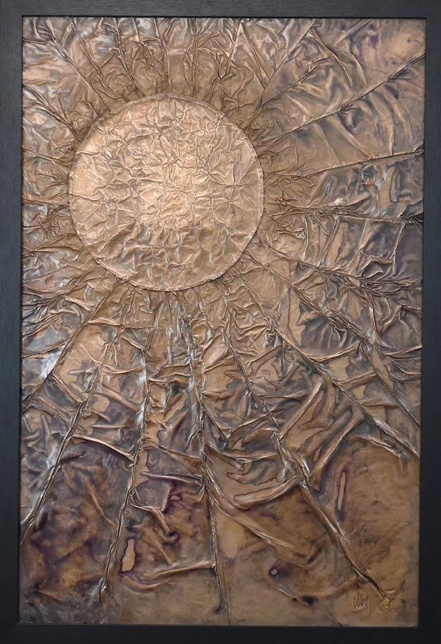 A luminous orb radiates through a fractured bronze field. Shown close up in a black frame.