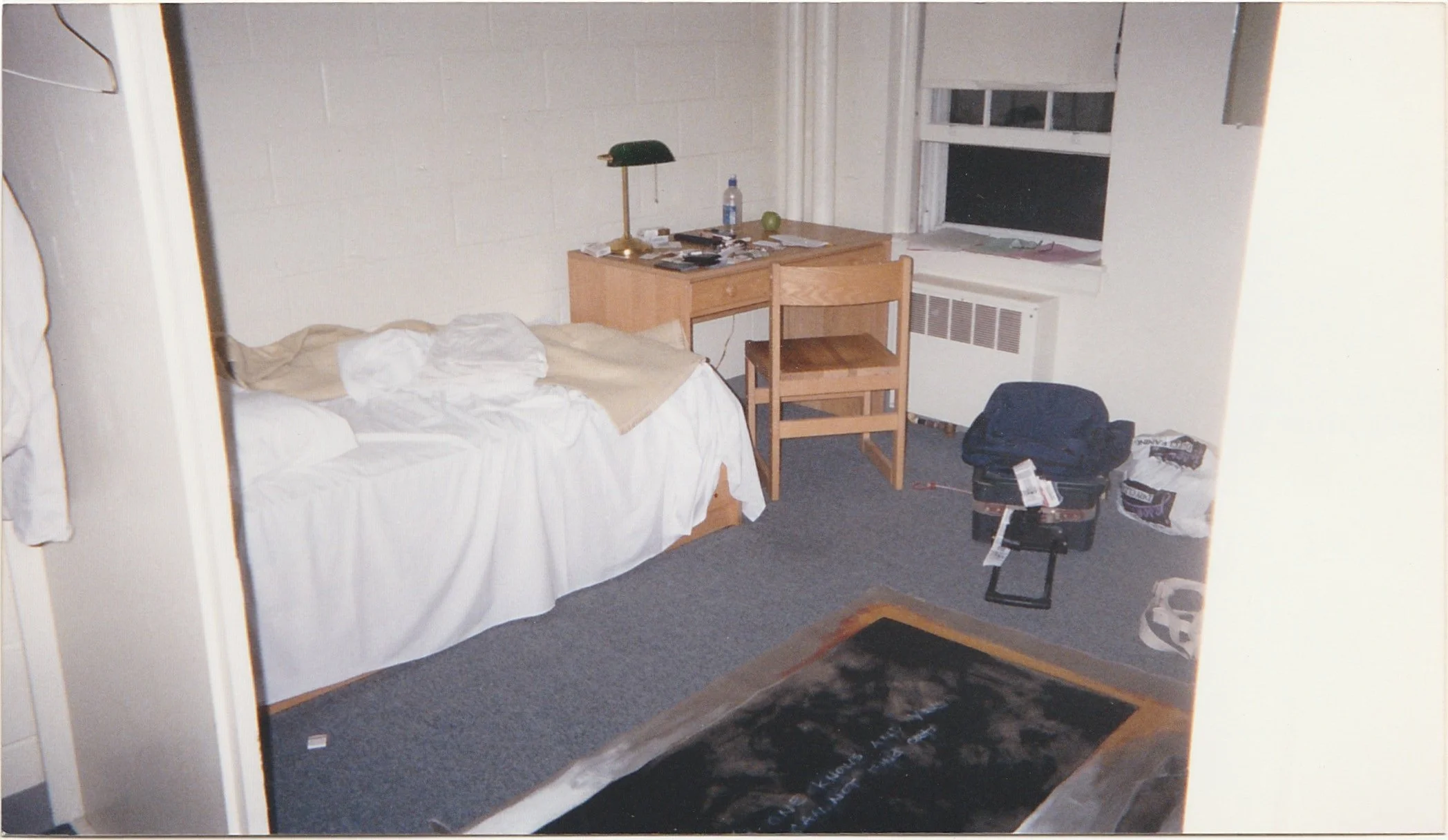 Modest hotel room with a neatly made bed, desk, and window.