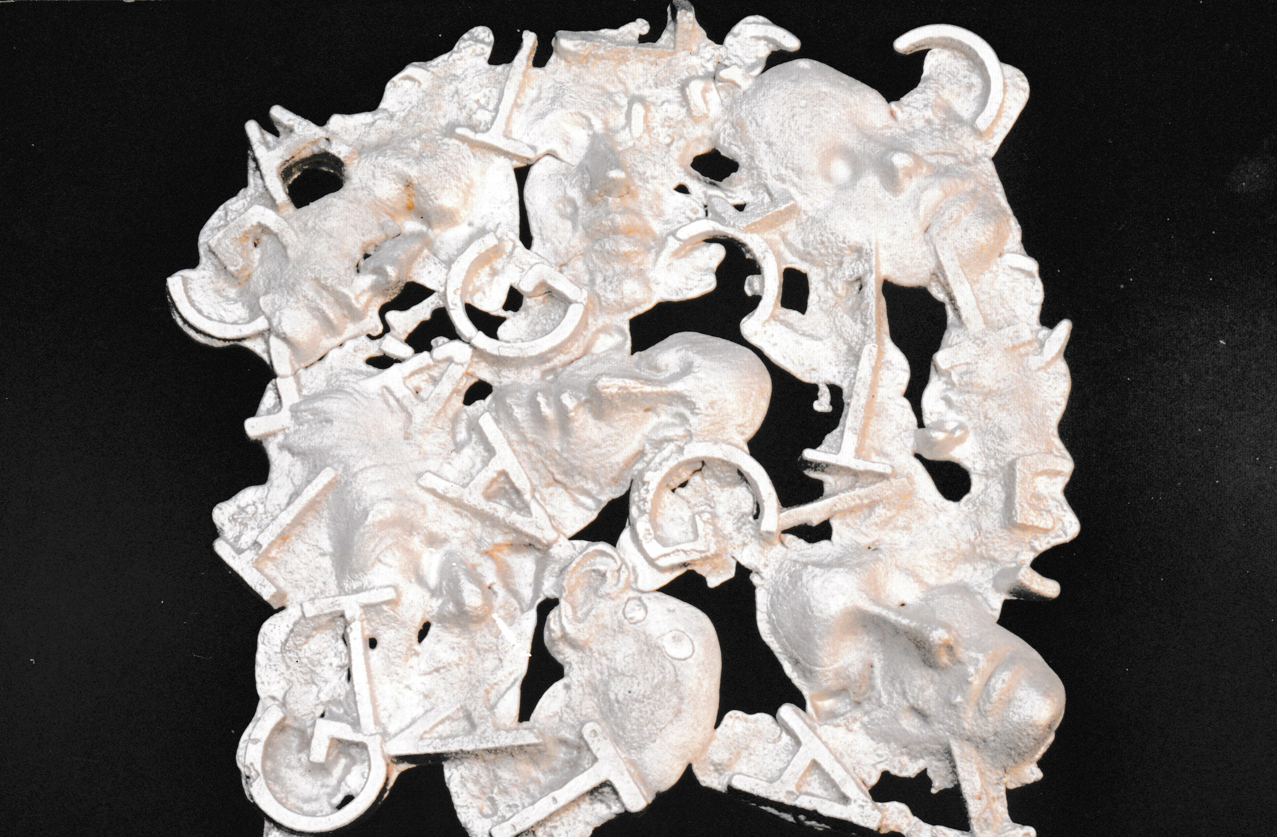 White relief sculpture composed of intertwined faces, letters, and abstract shapes arranged against a black background.