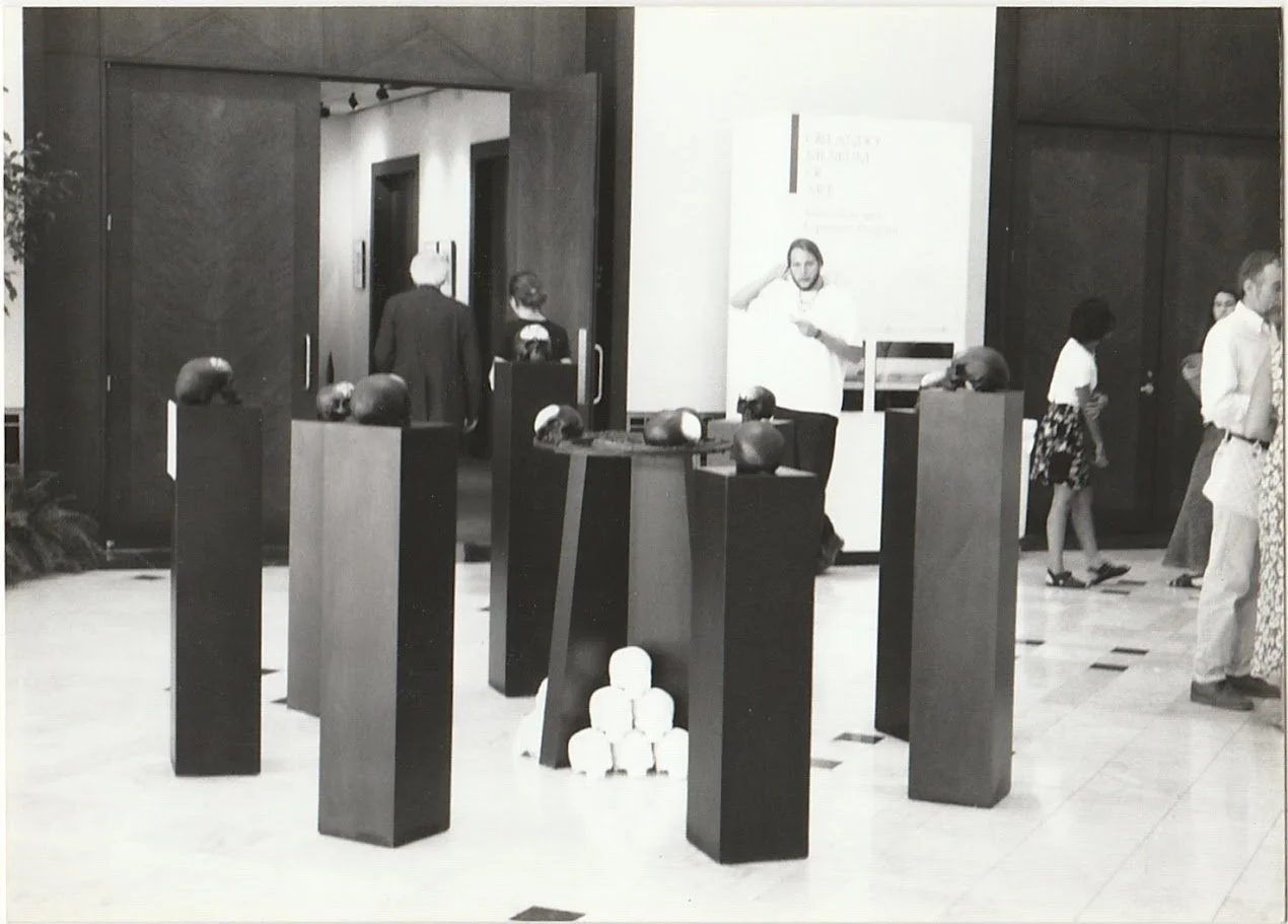Skull sculptures rest on tall rectangular pedestals, leading the viewer's eye through a carefully arranged exhibition of interconnected forms.