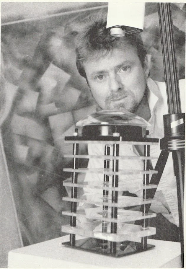 Whitney Wolf II standing behind a scientific sculpture that he created. Est 1980s