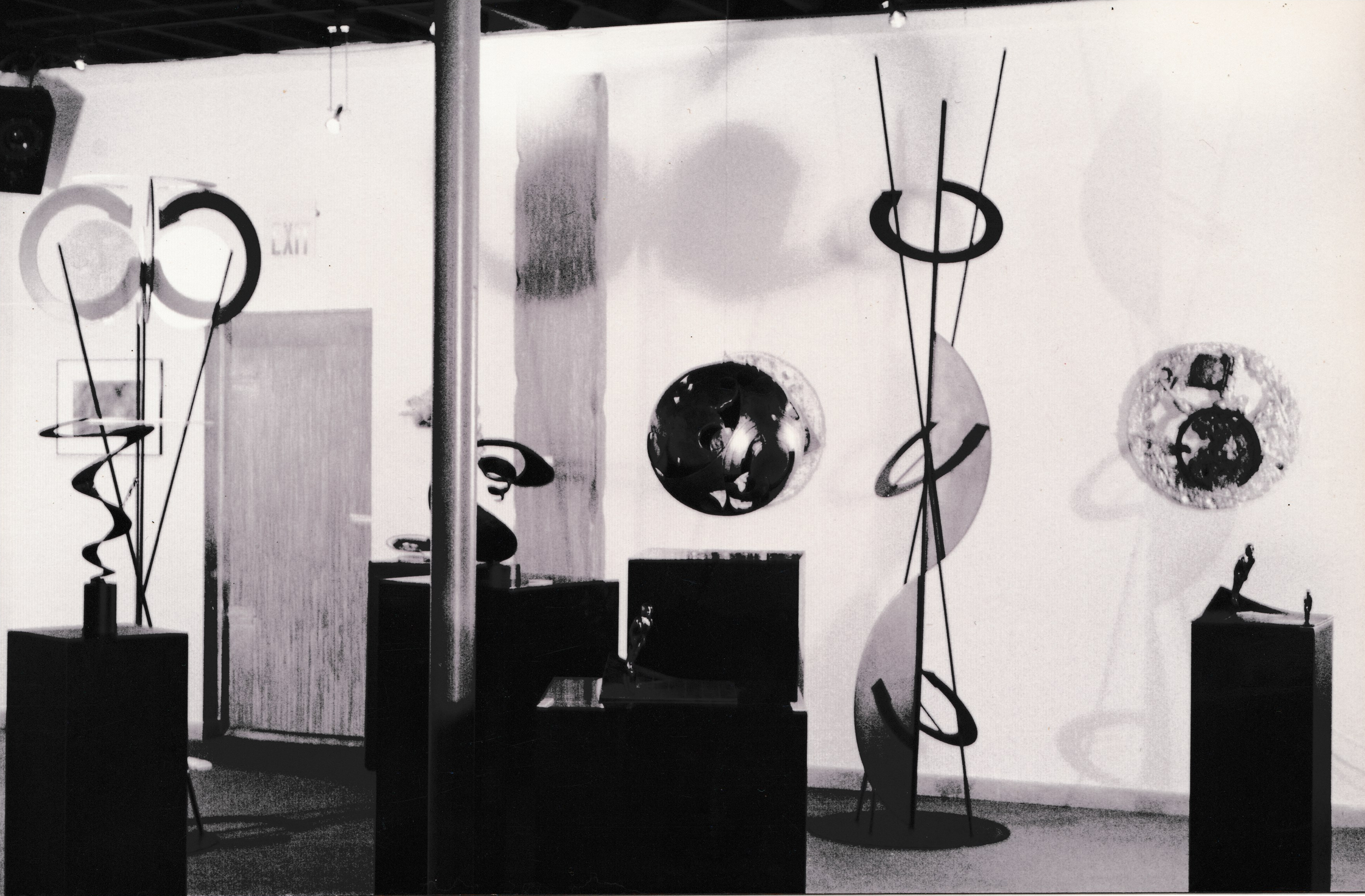 Gallery installation featuring multiple abstract sculptures and circular wall-mounted artworks.