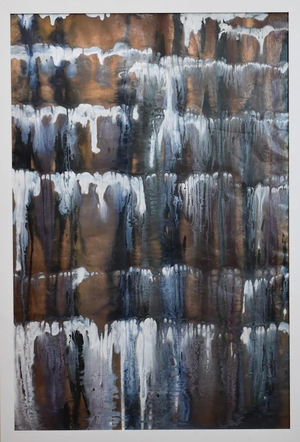 Layered white, blue, and bronze currents cascade across the surface. Shown close up in a white frame.