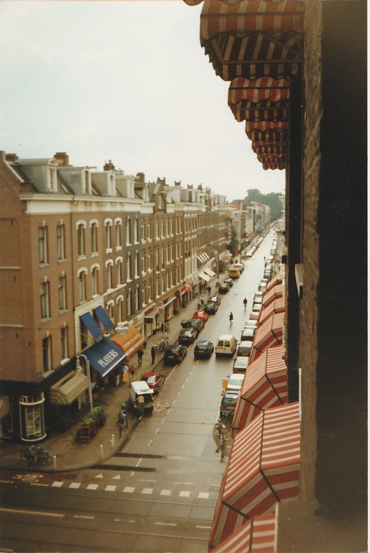 Long urban street lined with historic brick buildings and storefront awnings.