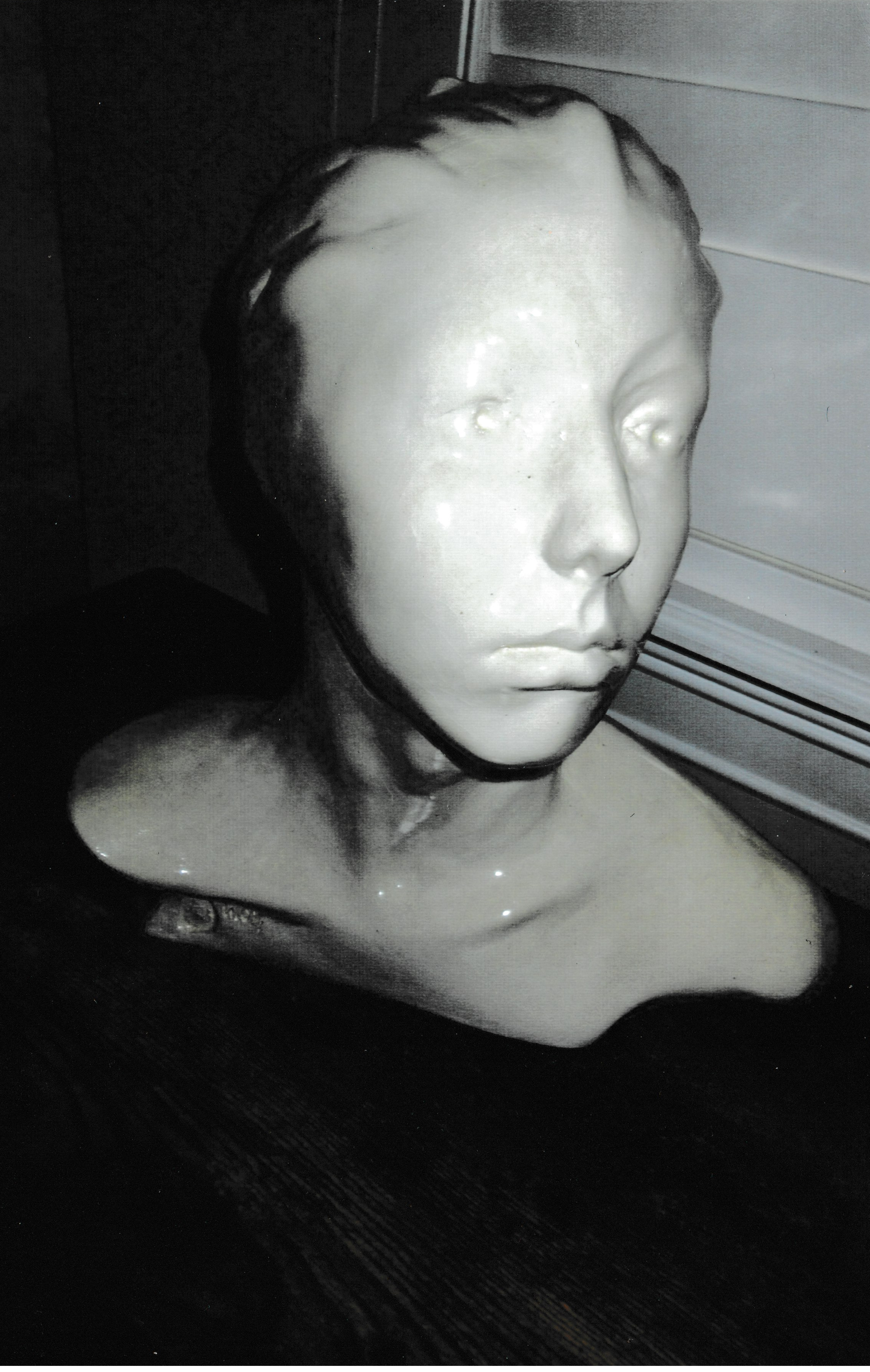 Ceramic life cast portrait with softly defined features and unfinished shoulders, conveying a sense of emergence from the material.