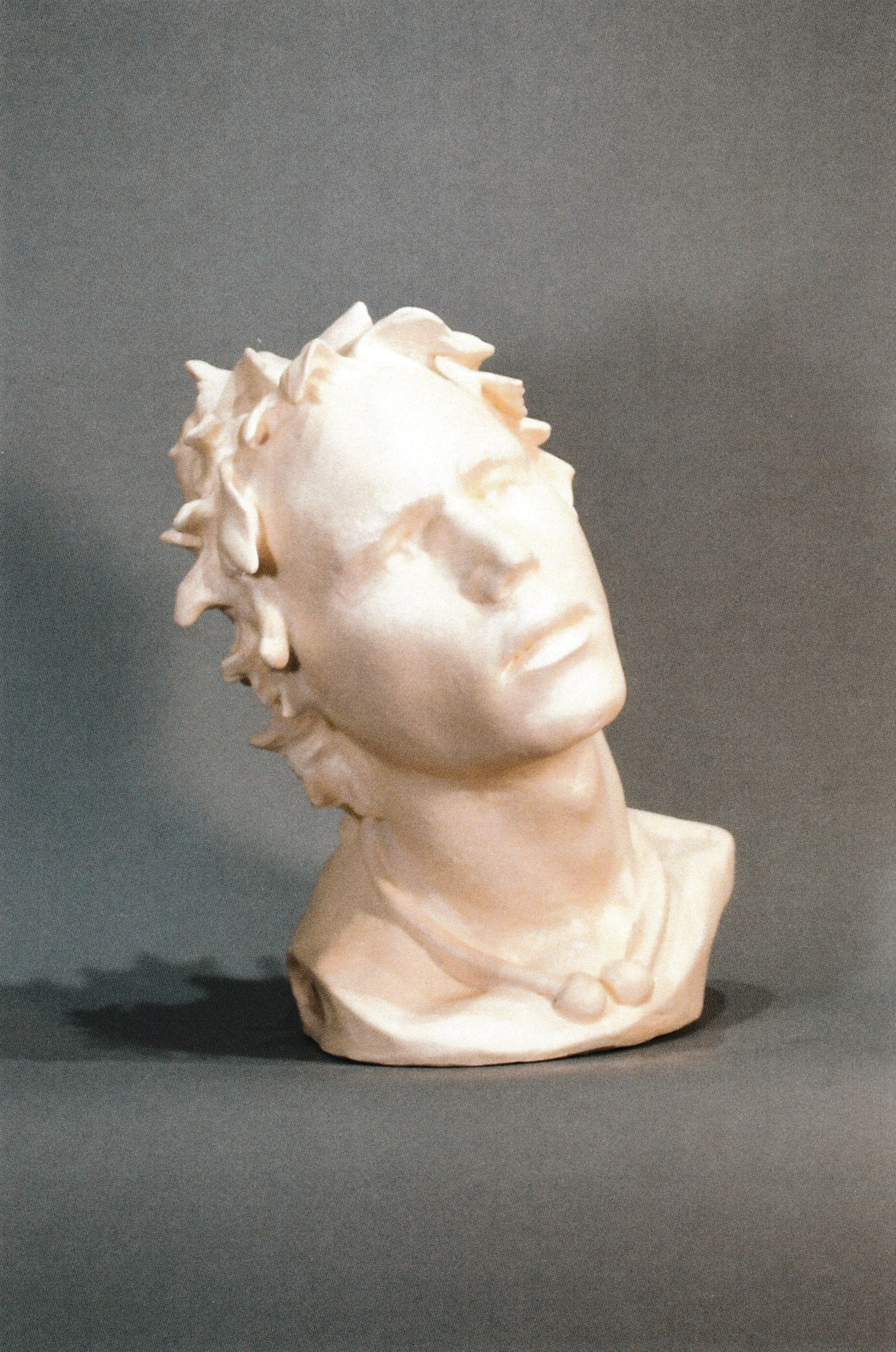 Stylized life-mask-derived ceramic portrait framed by jagged petal-like forms radiating outward from the face.