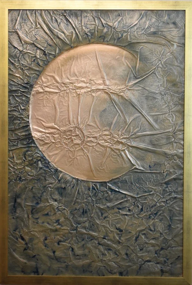 A copper orb emerges from a dark, textured metallic field. Shown close up in a golden frame.