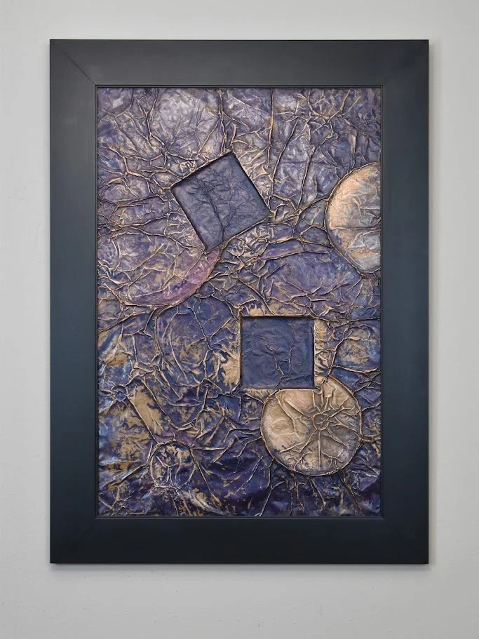 Geometric forms float within a fractured violet field. Displayed framed on a white wall.
