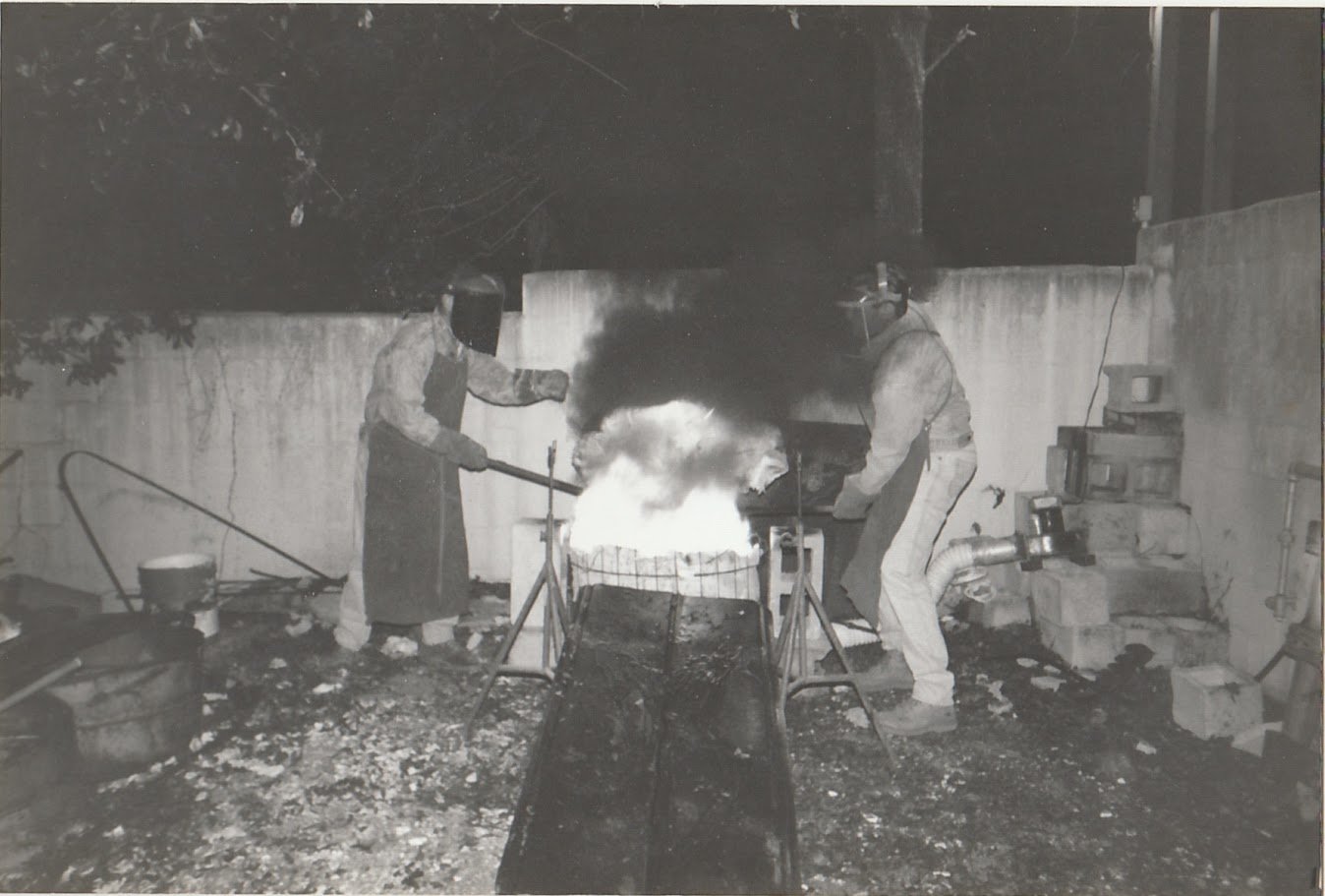 Whitney Wolf II teaching students to cast bronze. Black-and-white photo. EST 1980s