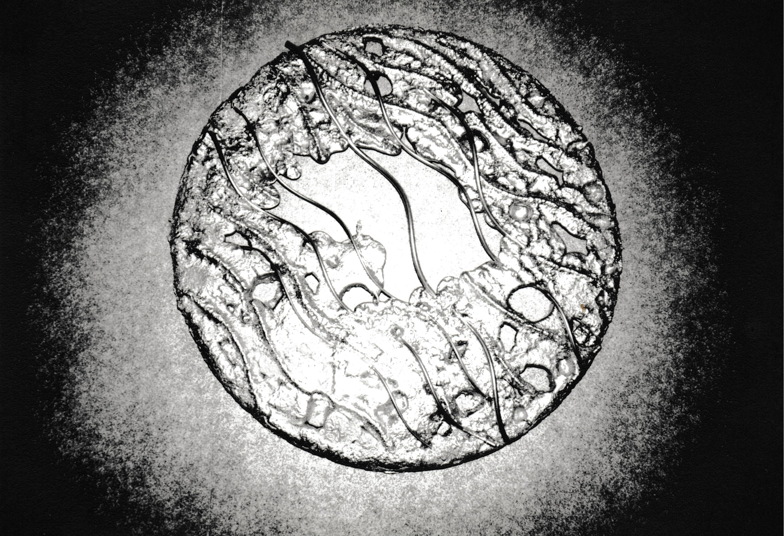 Circular relief sculpture with textured patterns radiating around an open central form.