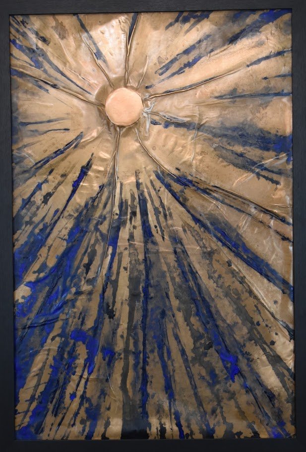 Radiating blue and gold lines burst outward from a luminous center. Shown close up in a black frame.