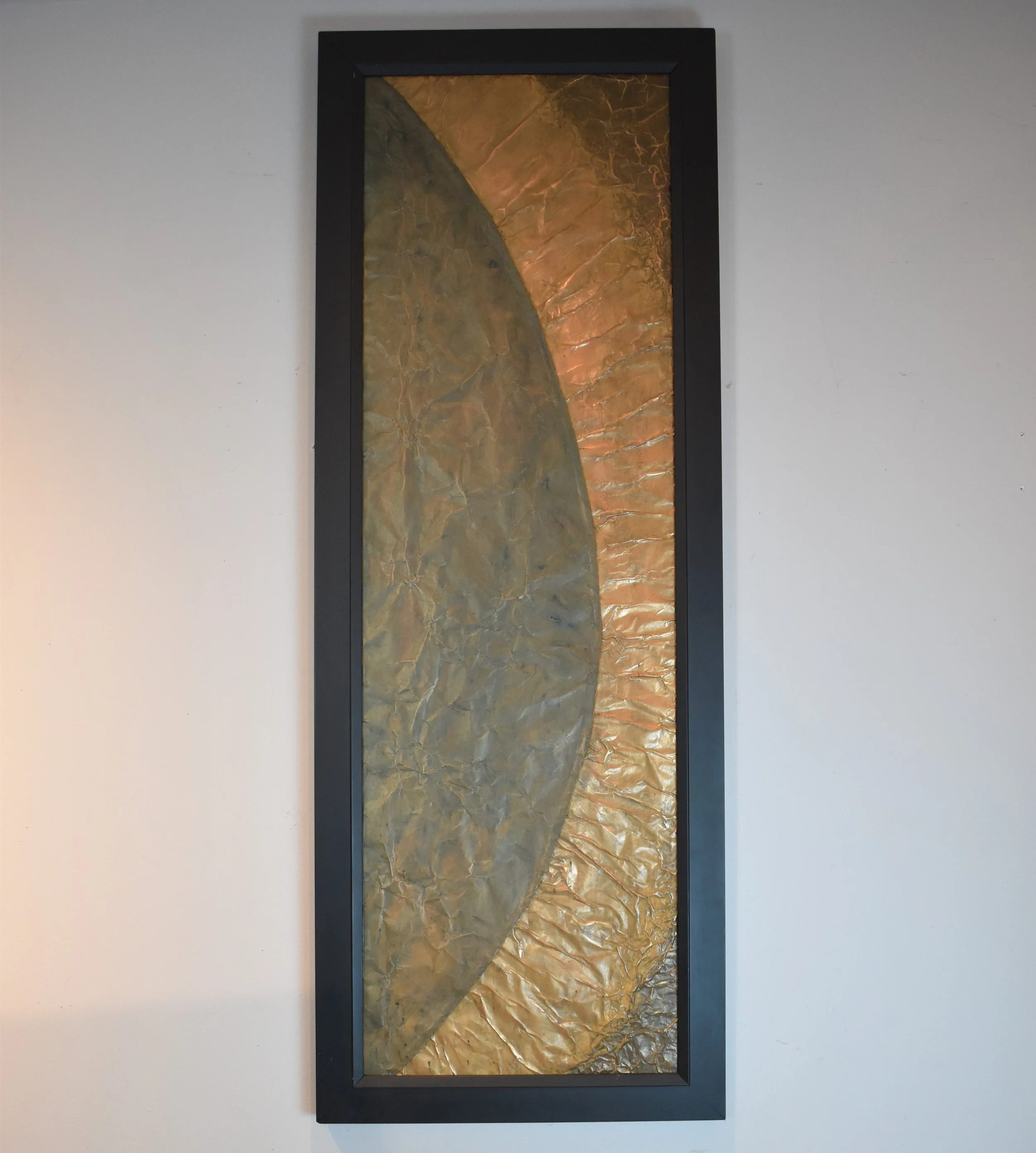 A dark planetary arc emerges against a radiant golden field. Displayed framed on a white wall.