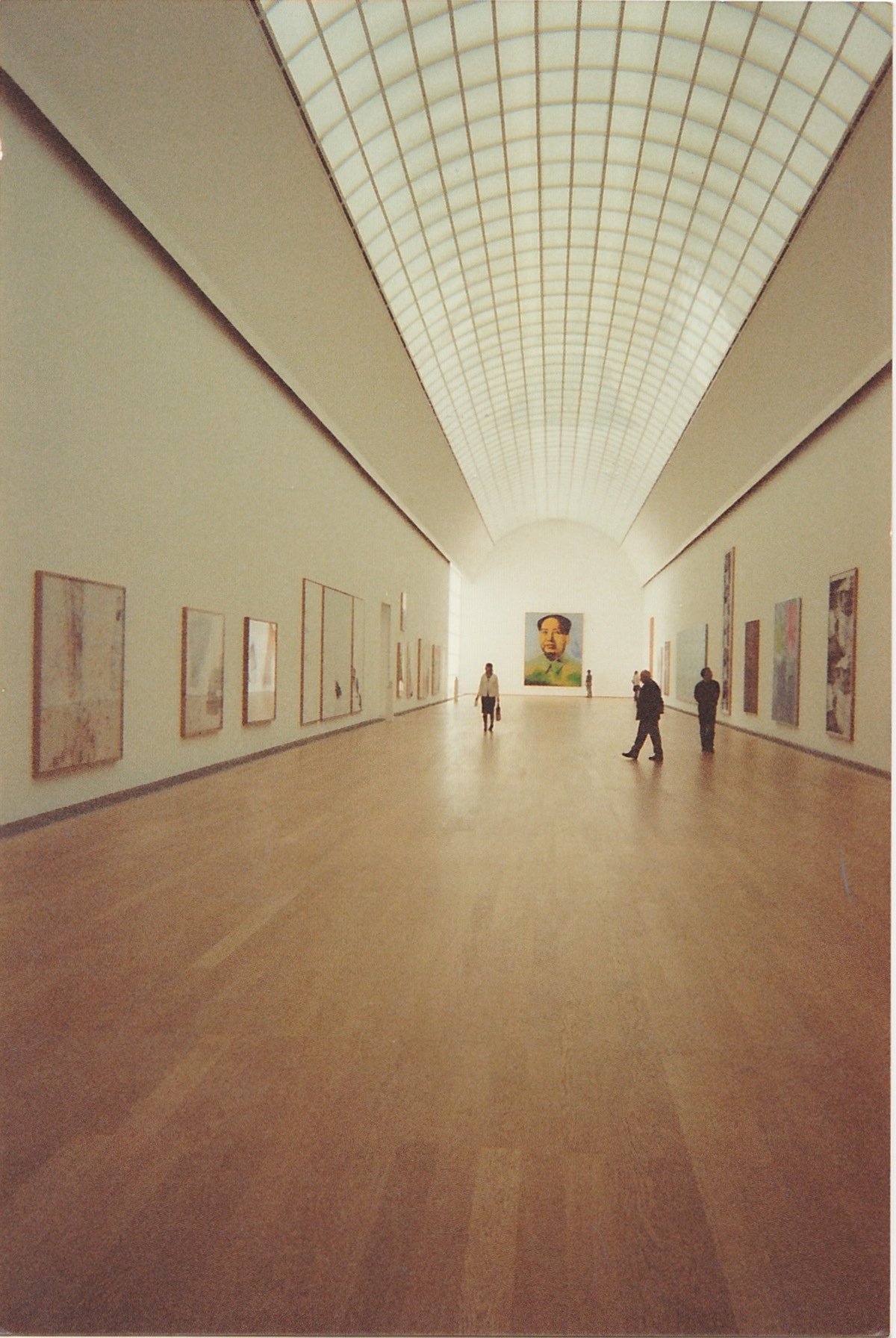Long minimalist museum gallery lined with framed artworks.