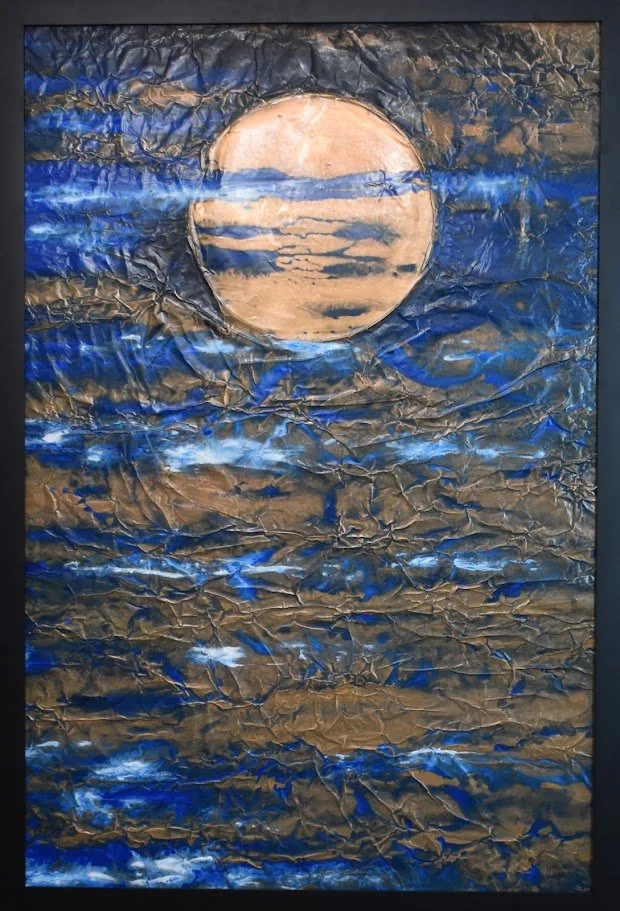 A golden orb floats within turbulent currents of deep blue. Shown close up in a black frame.