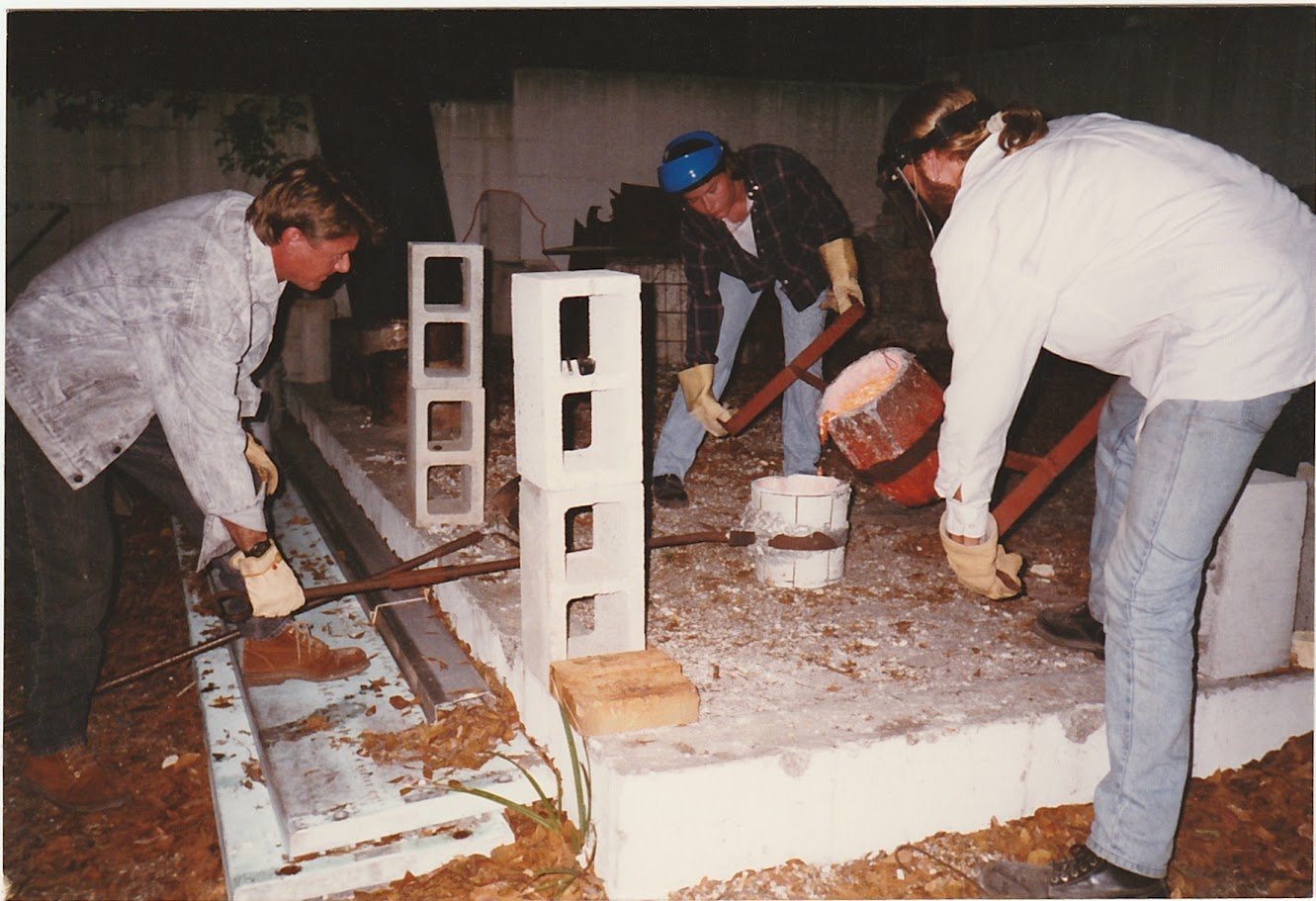 Whitney Wolf II finishing off a bronze piece, with the help of two students. EST 1980s