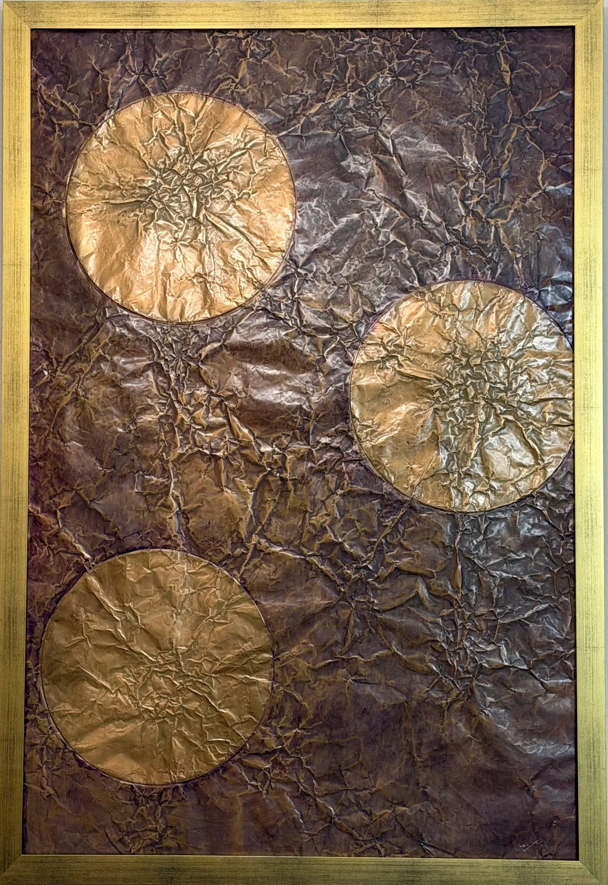 Three golden orbs float within a dark metallic field. Shown close up with a golden frame.