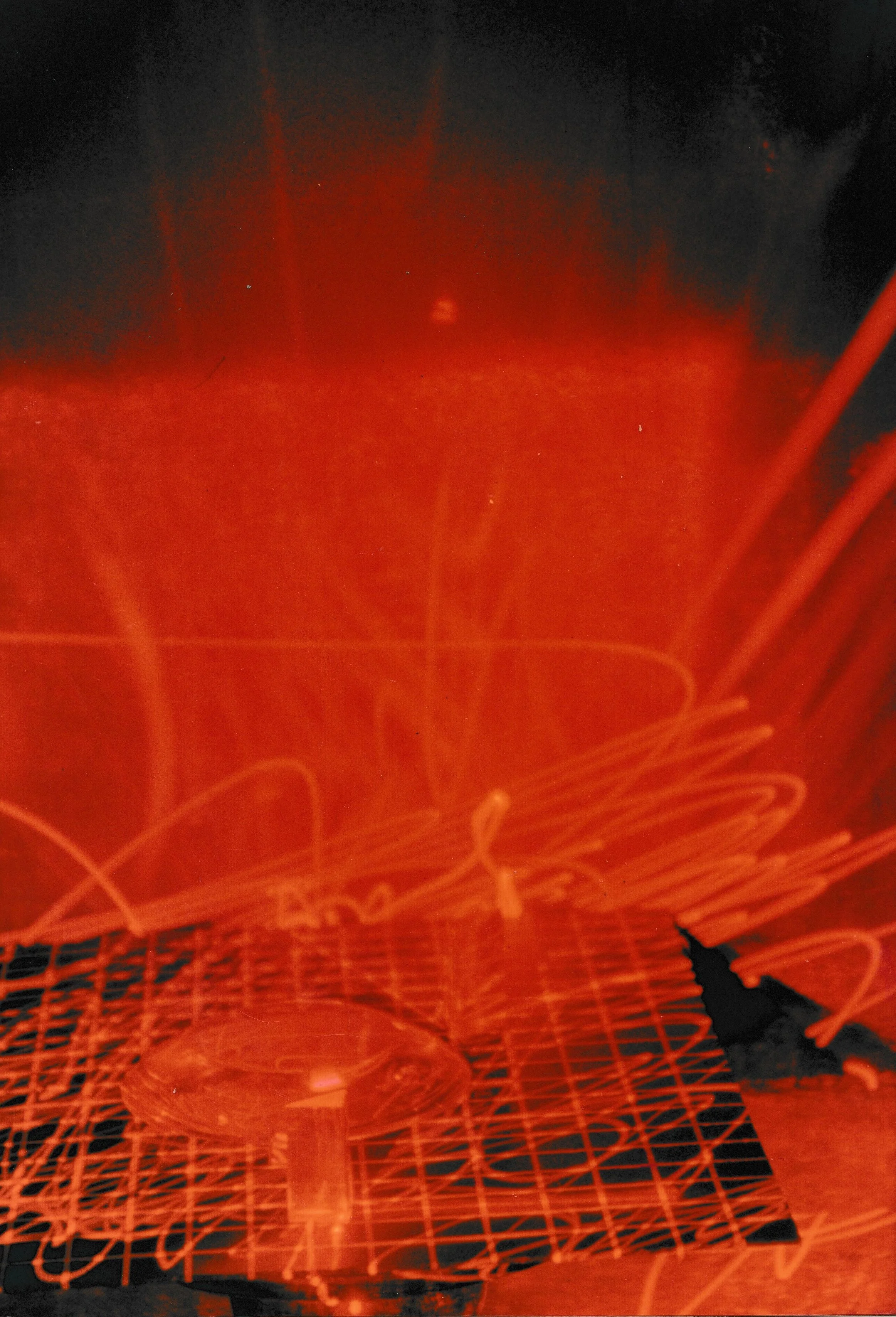Long-exposure photograph of red laser light forming circular spirals above sculptural forms in a dark gallery.