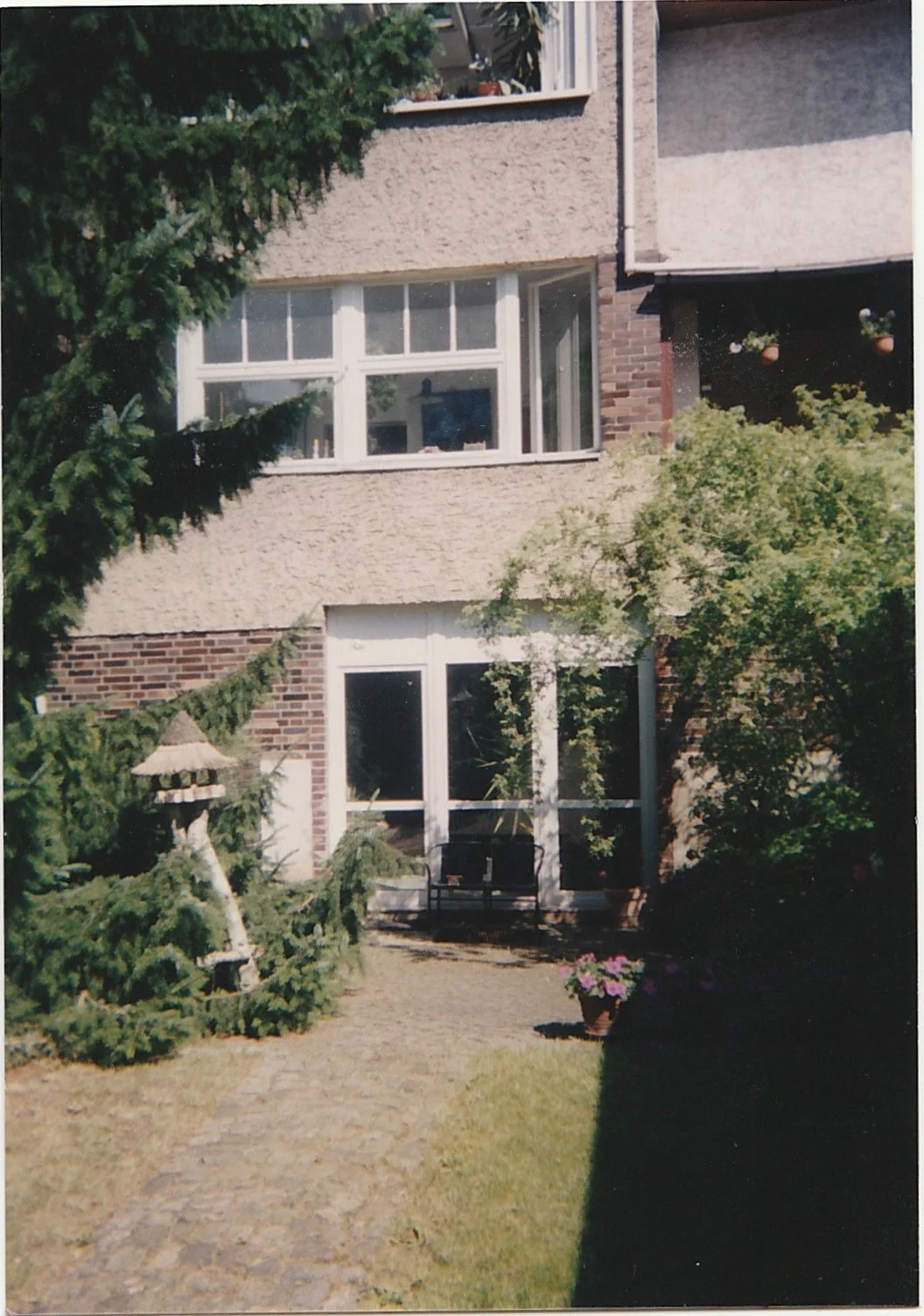 Residential garden courtyard bordered by trees and apartment buildings.