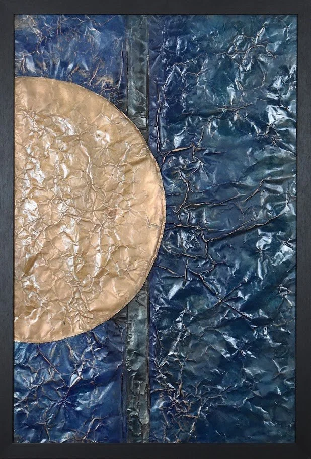 A golden orb emerges against a deep blue metallic field. Shown close up in a black frame.