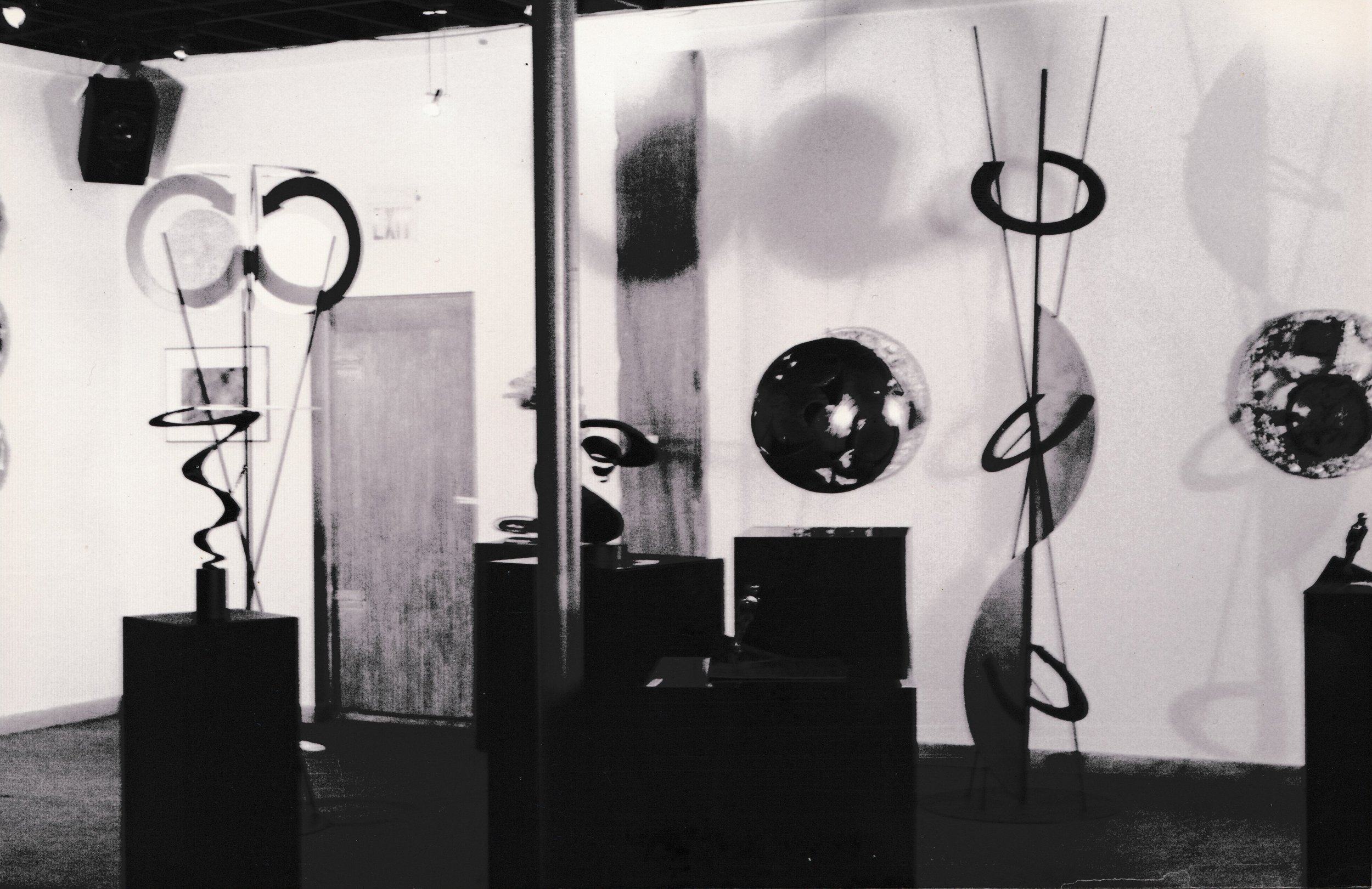 Wide view of an exhibition space displaying abstract sculptures, circular wall pieces, and geometric forms.