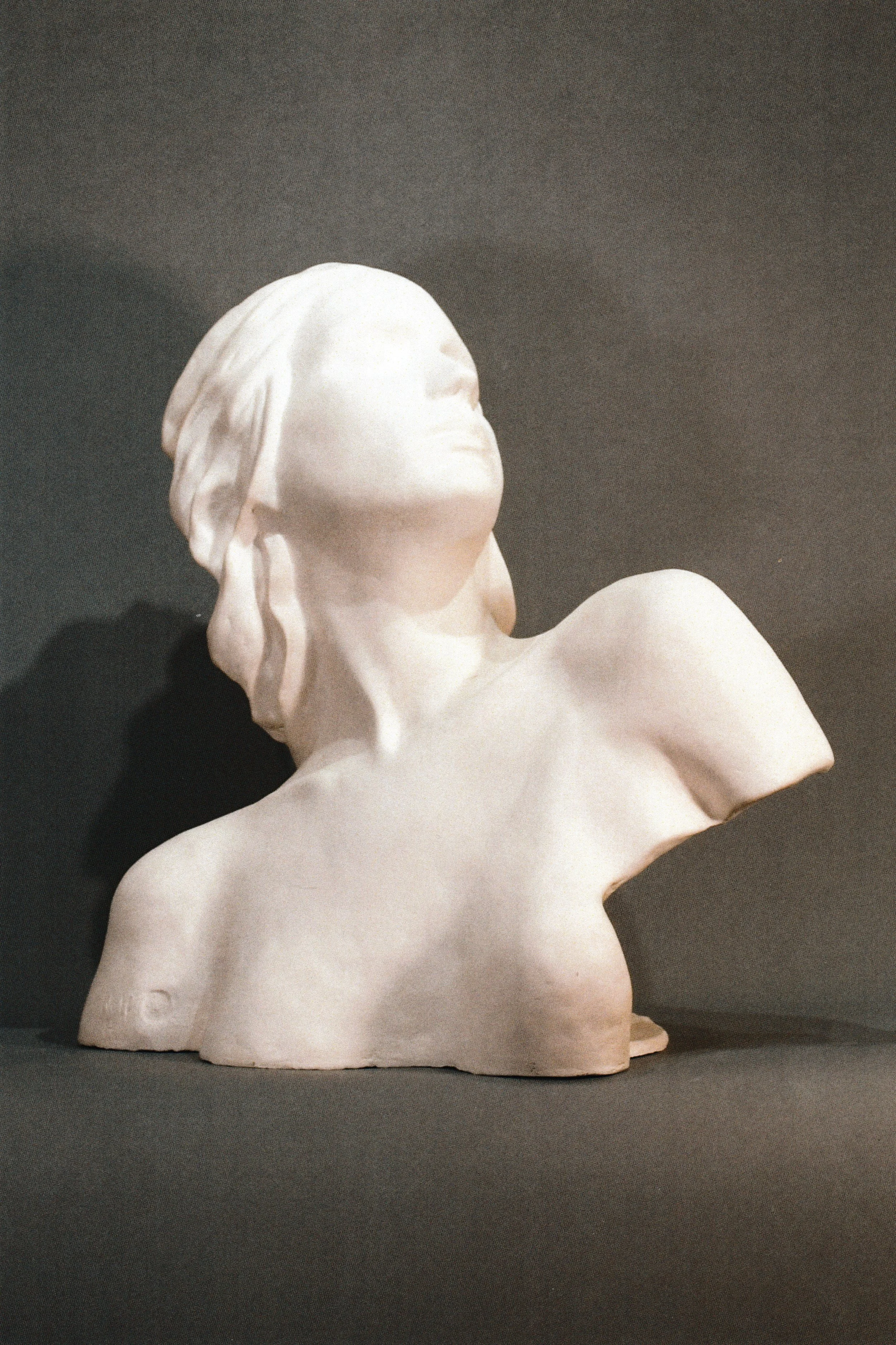 Ceramic life mask bust of a woman arching backward, her face turned toward the light.