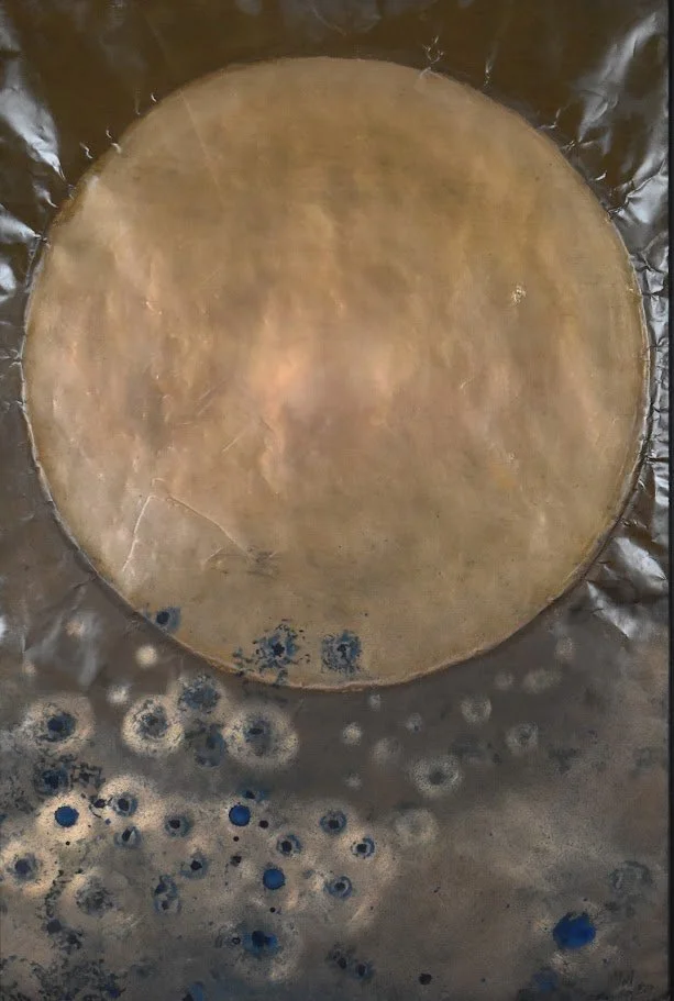 A textured metallic composition dominated by a large golden orb above a field of scattered blue and silver circular forms. Shown close up without a frame.