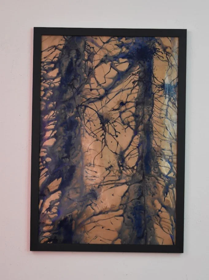 Branching blue currents spread across a warm copper field. Displayed framed on a white wall.