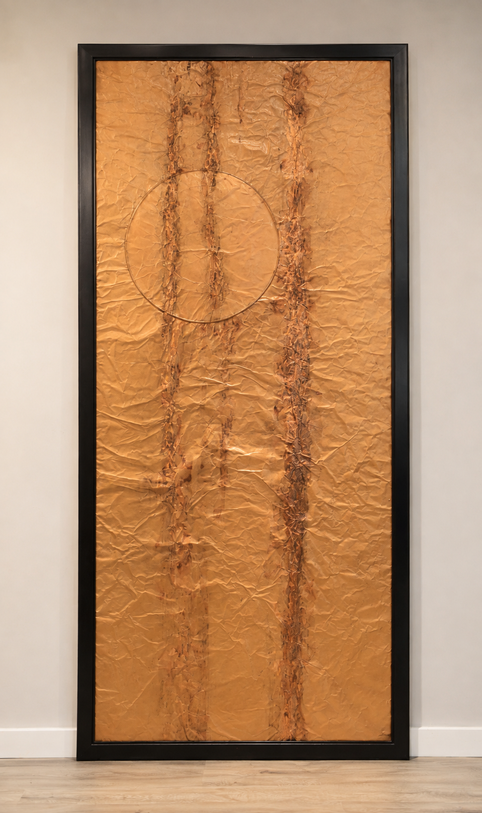 A circular form intersects vertical lines across a textured copper field. Displayed framed on a white wall.
